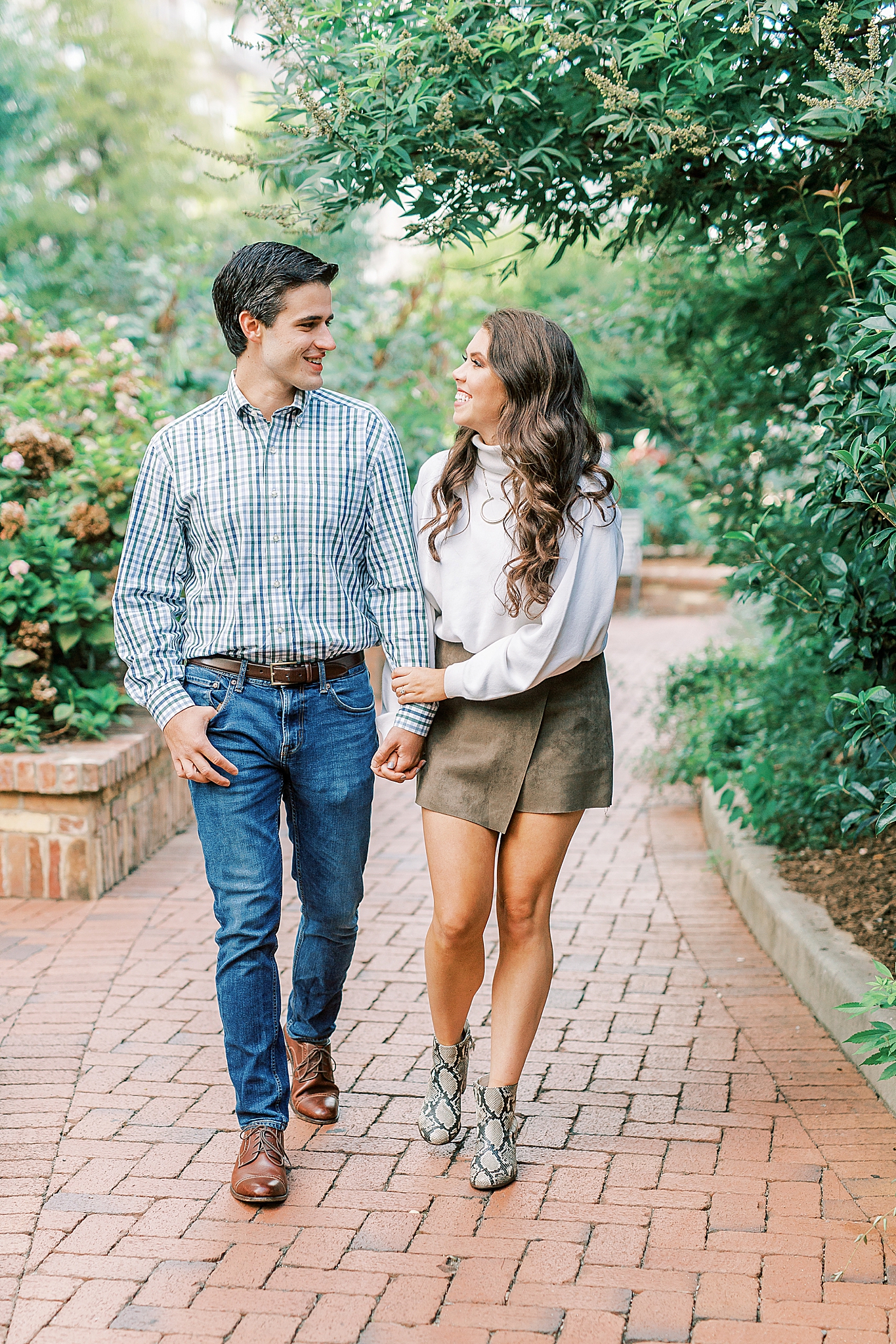 engaged couple walks through city park