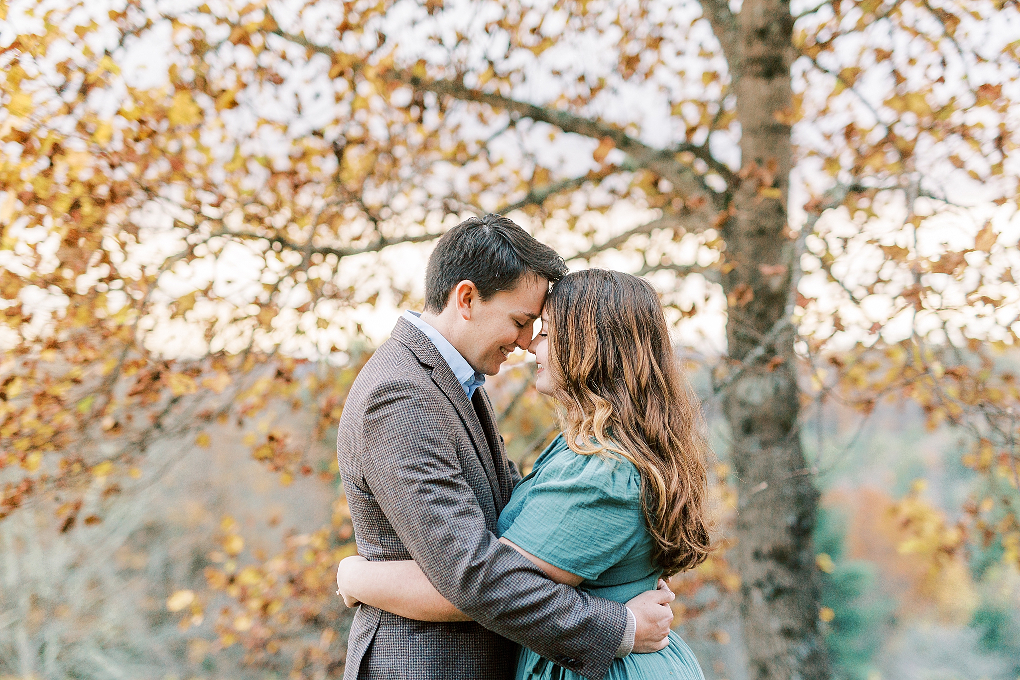 bride and groom stand nose to nose during fall engagement photos