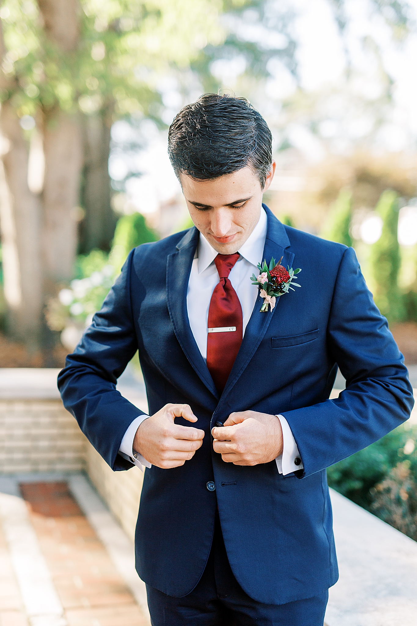 groom adjusts navy suit jacket before first look