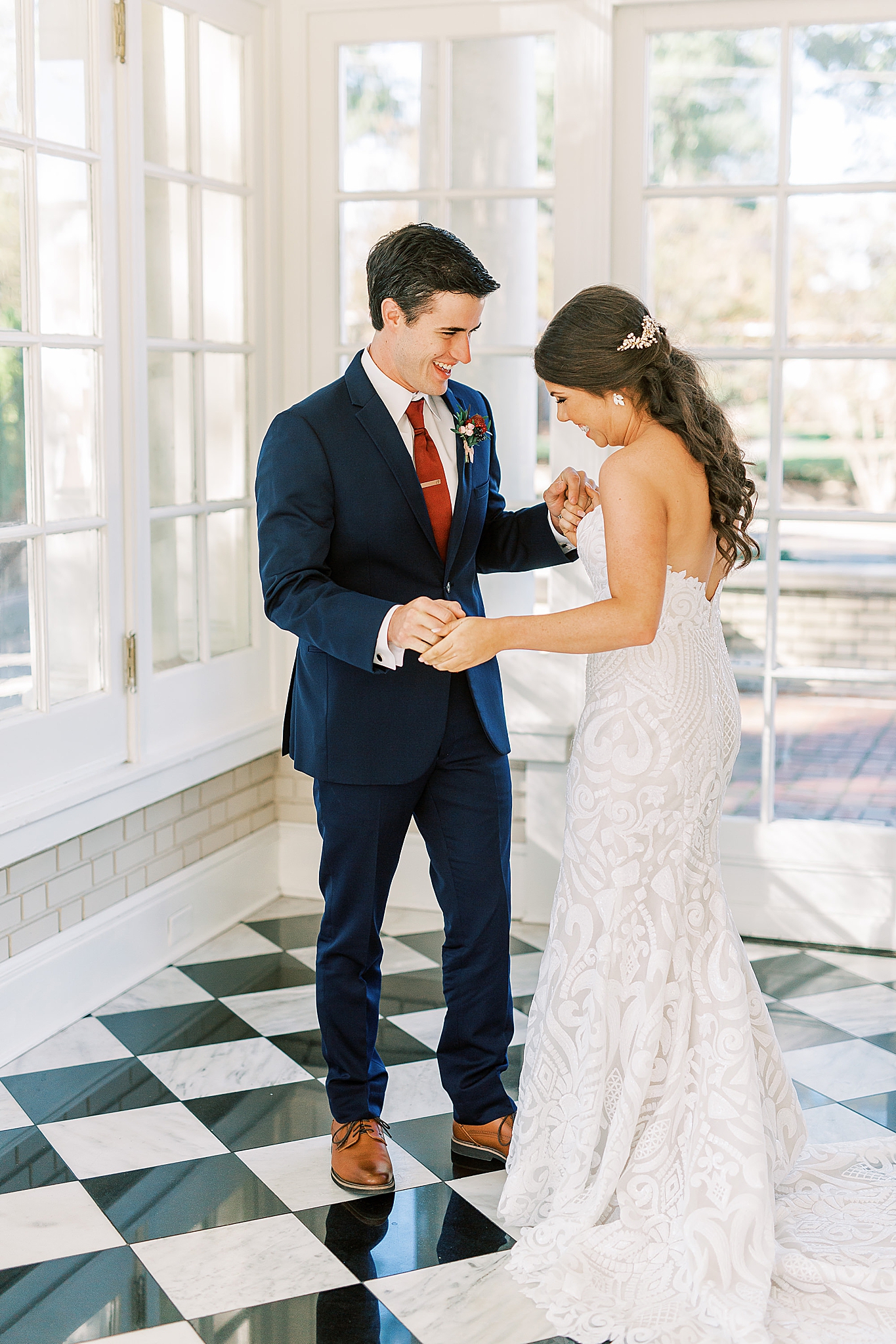 groom looks at bride's gown during first look
