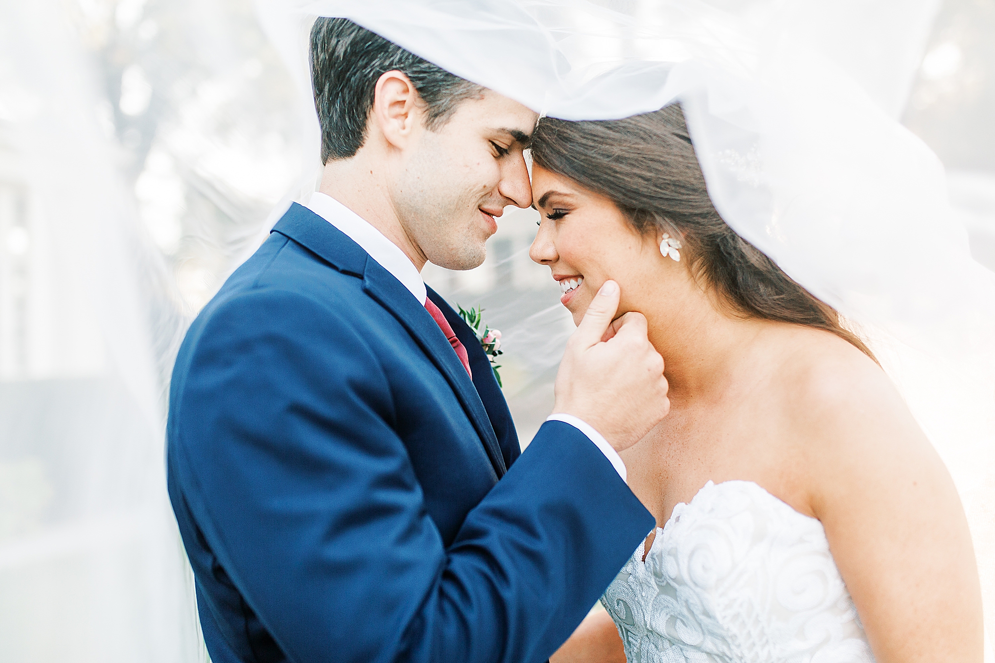 bride and groom cuddle under veil