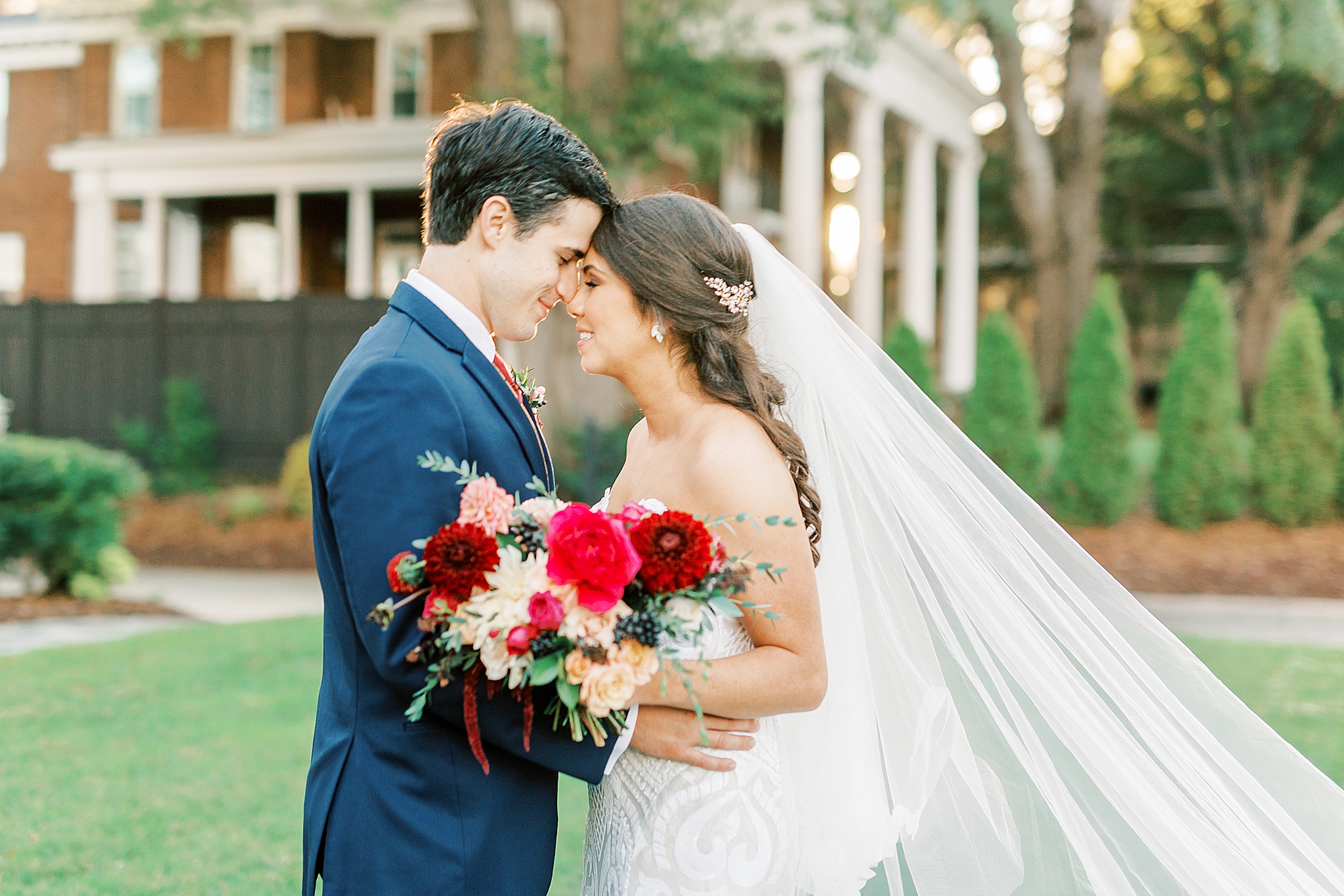 bride and groom pose together with veil floating