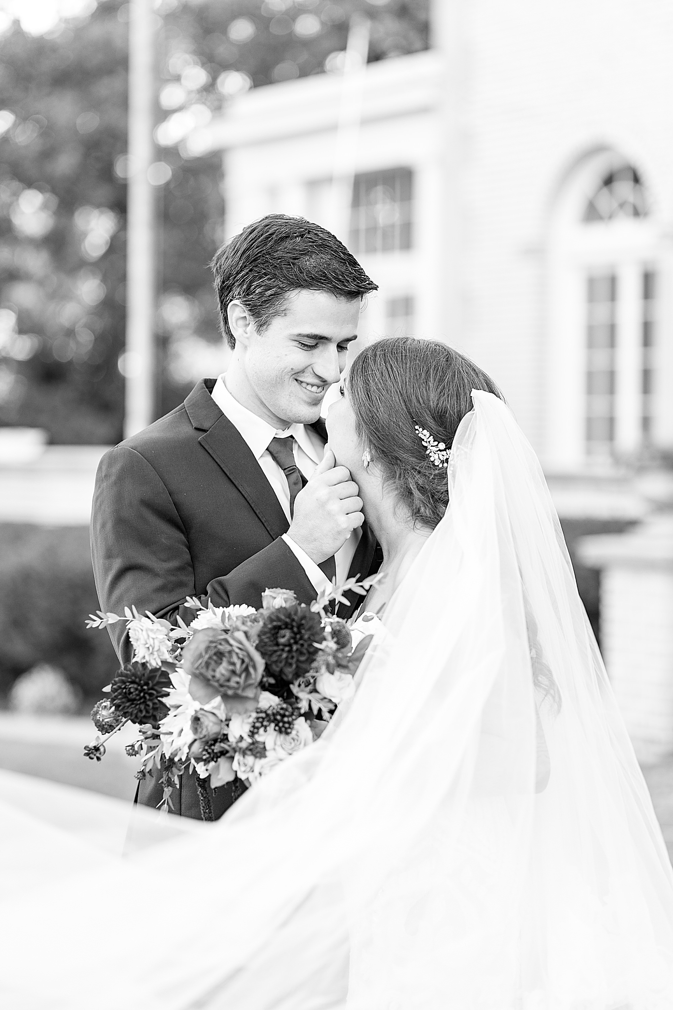 bride and groom look at each other with veil