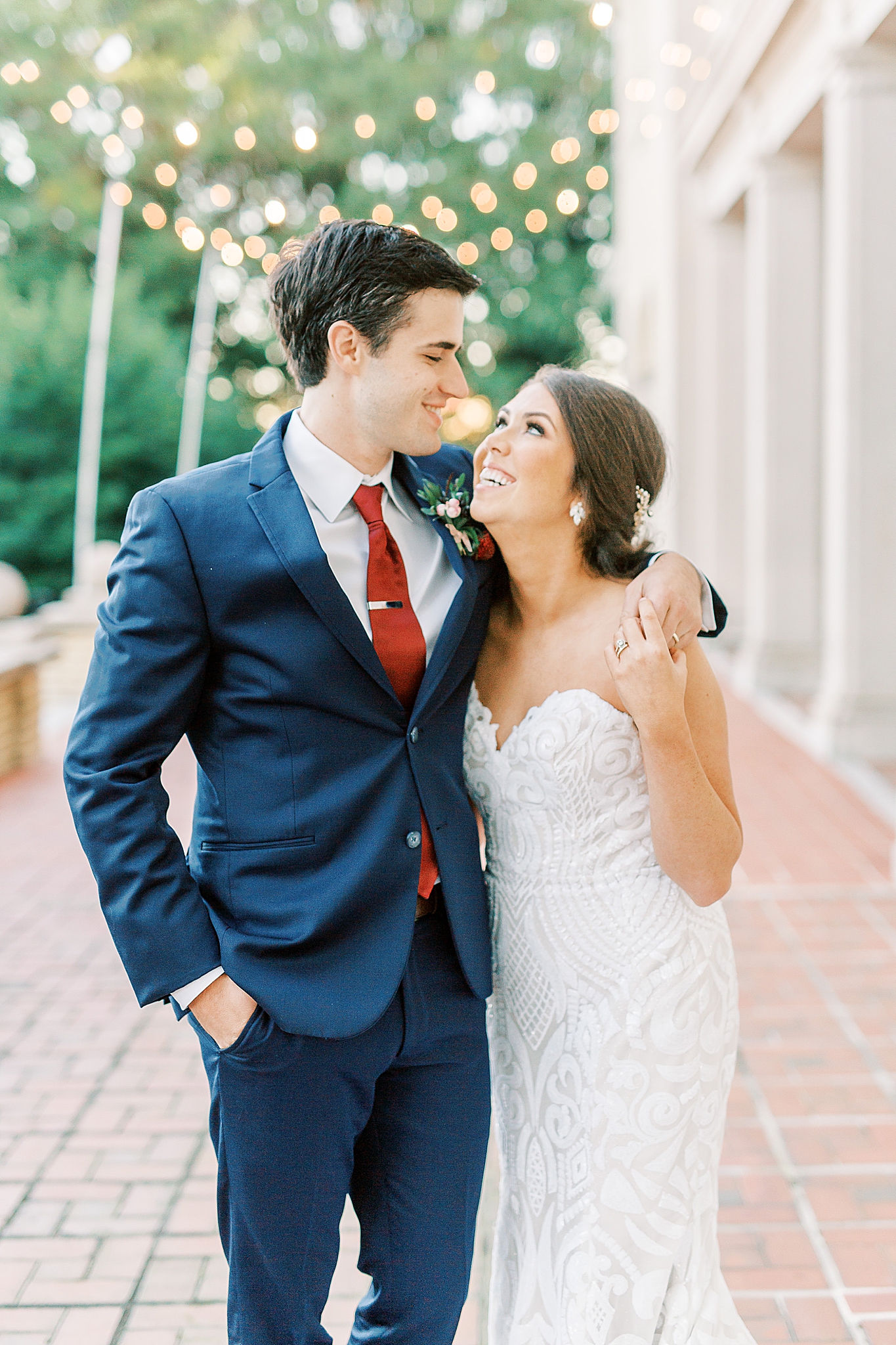 bride and groom look at each other with twinkling lights behind them