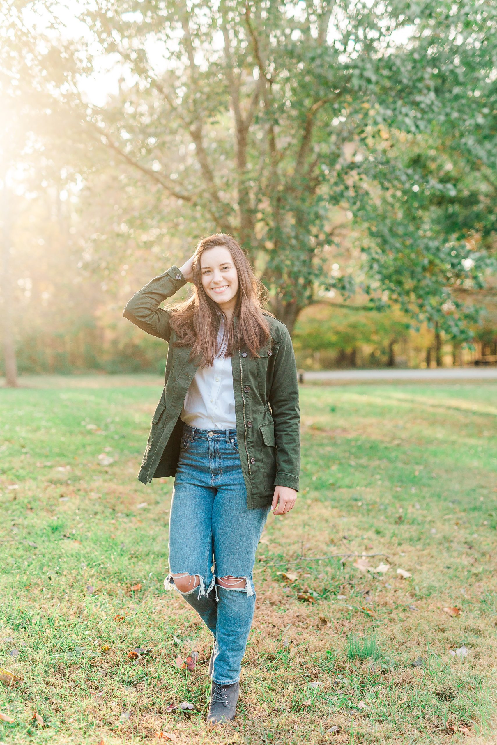 senior in green jacket and jeans poses during Sloan Park photos