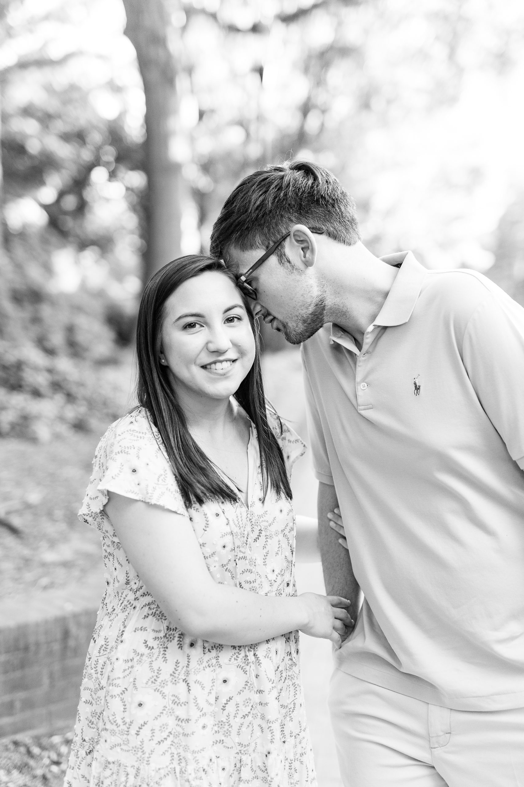 groom whispers in bride's ear during summer engagement photos