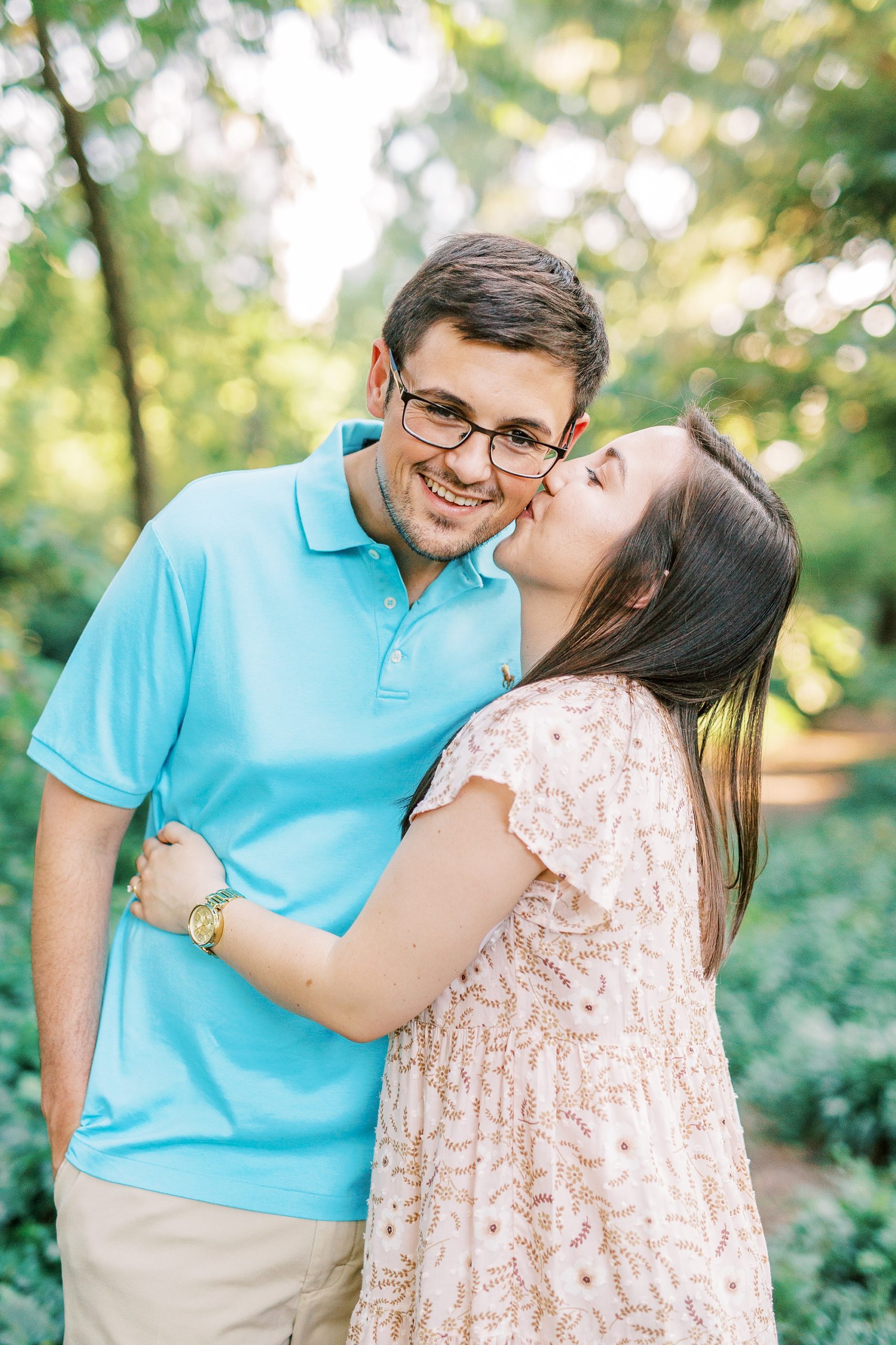 bride kisses groom's cheek during Fourth Ward Park engagement photos