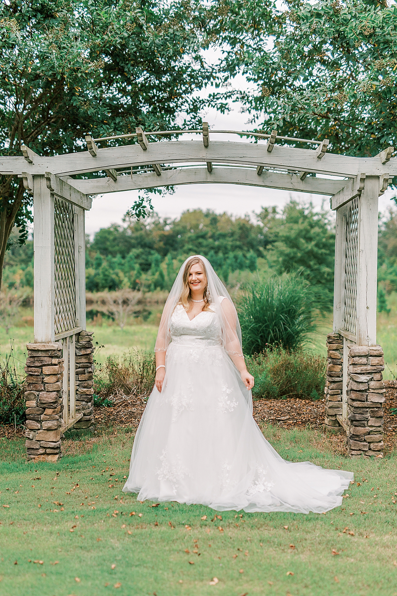 The Arbors bridal portraits of bride posing in front of wooden arbor