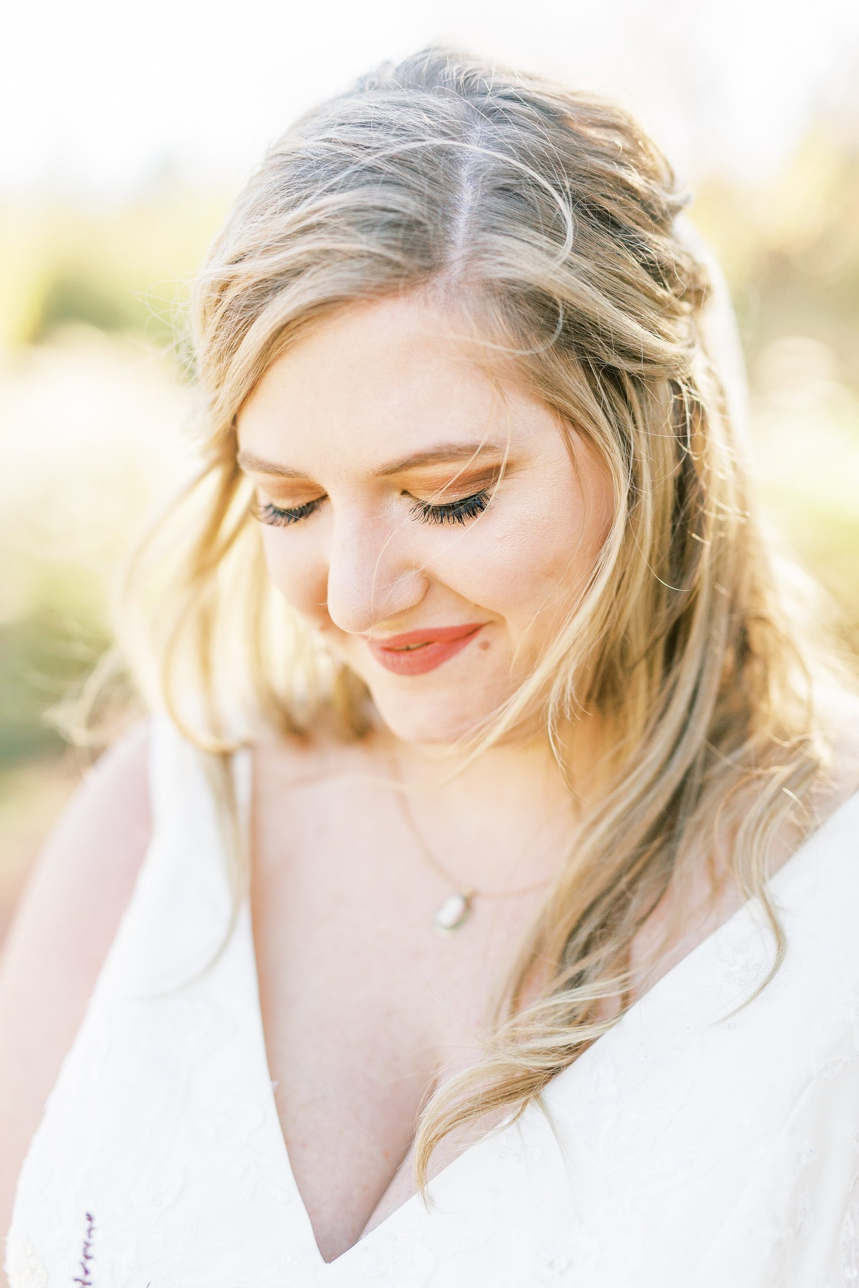 bride smiles down at bouquet