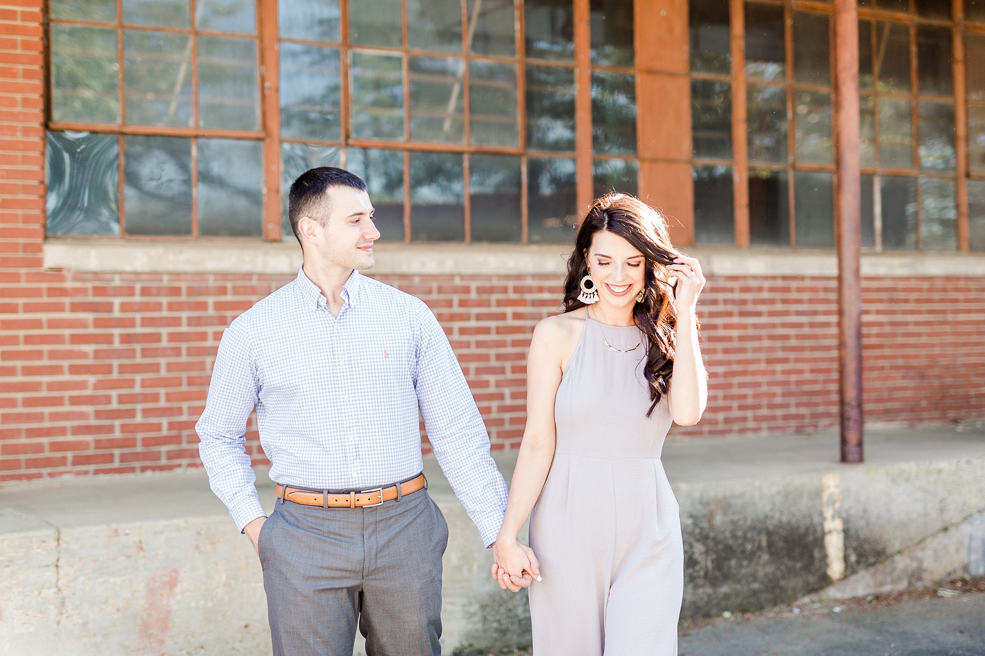 bride pushes hair back while walking with groom in Camp North End