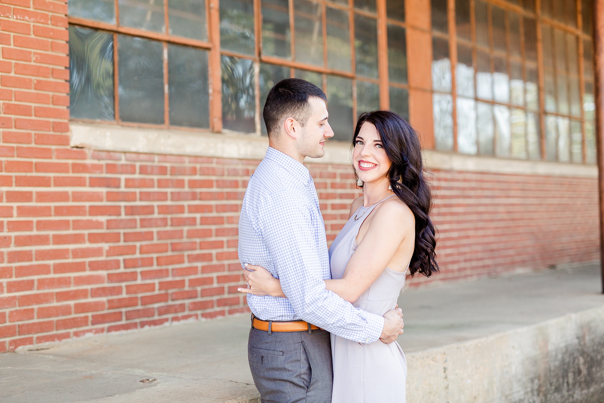 engaged couple poses by warehouse in Camp North End