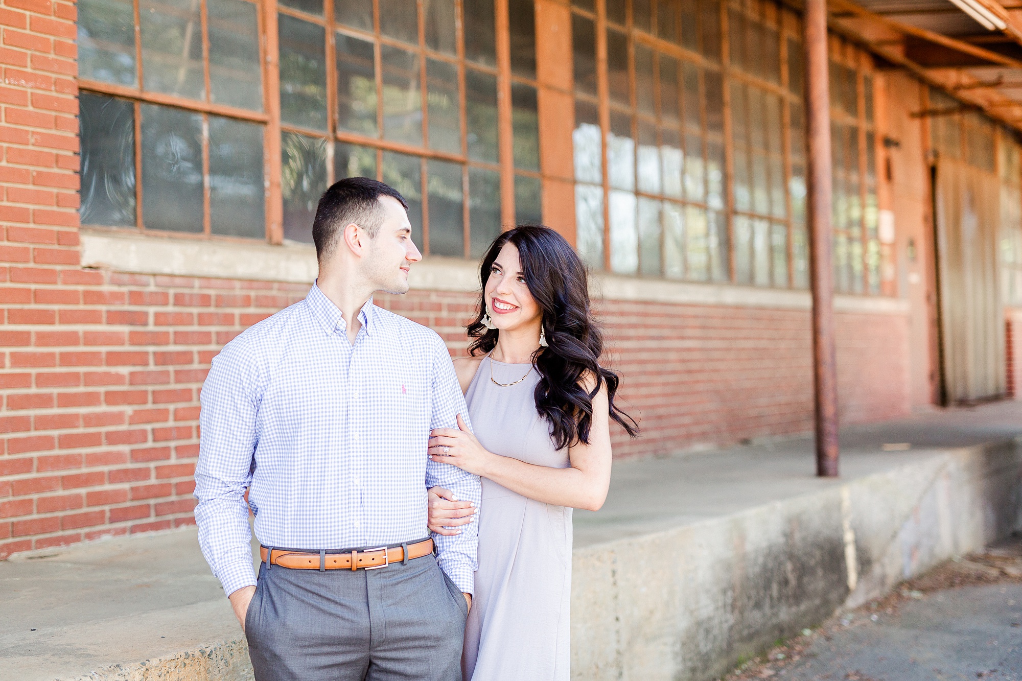 bride stands behind groom and looks over his shoulder at him