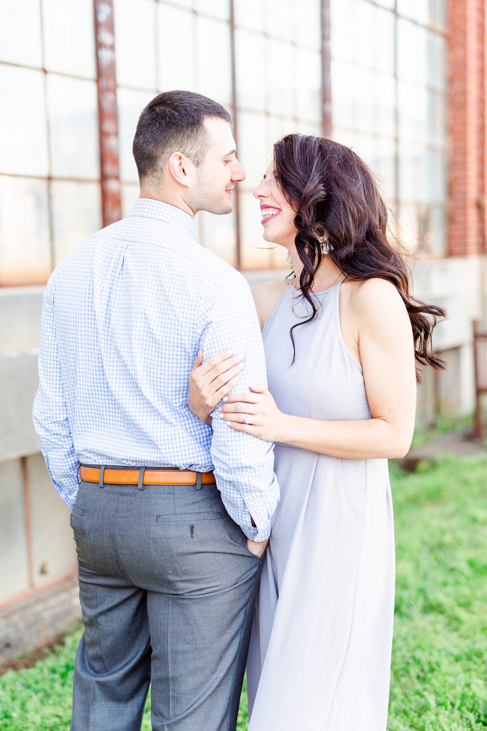 bride and groom look at each other in front of industrial warehouse