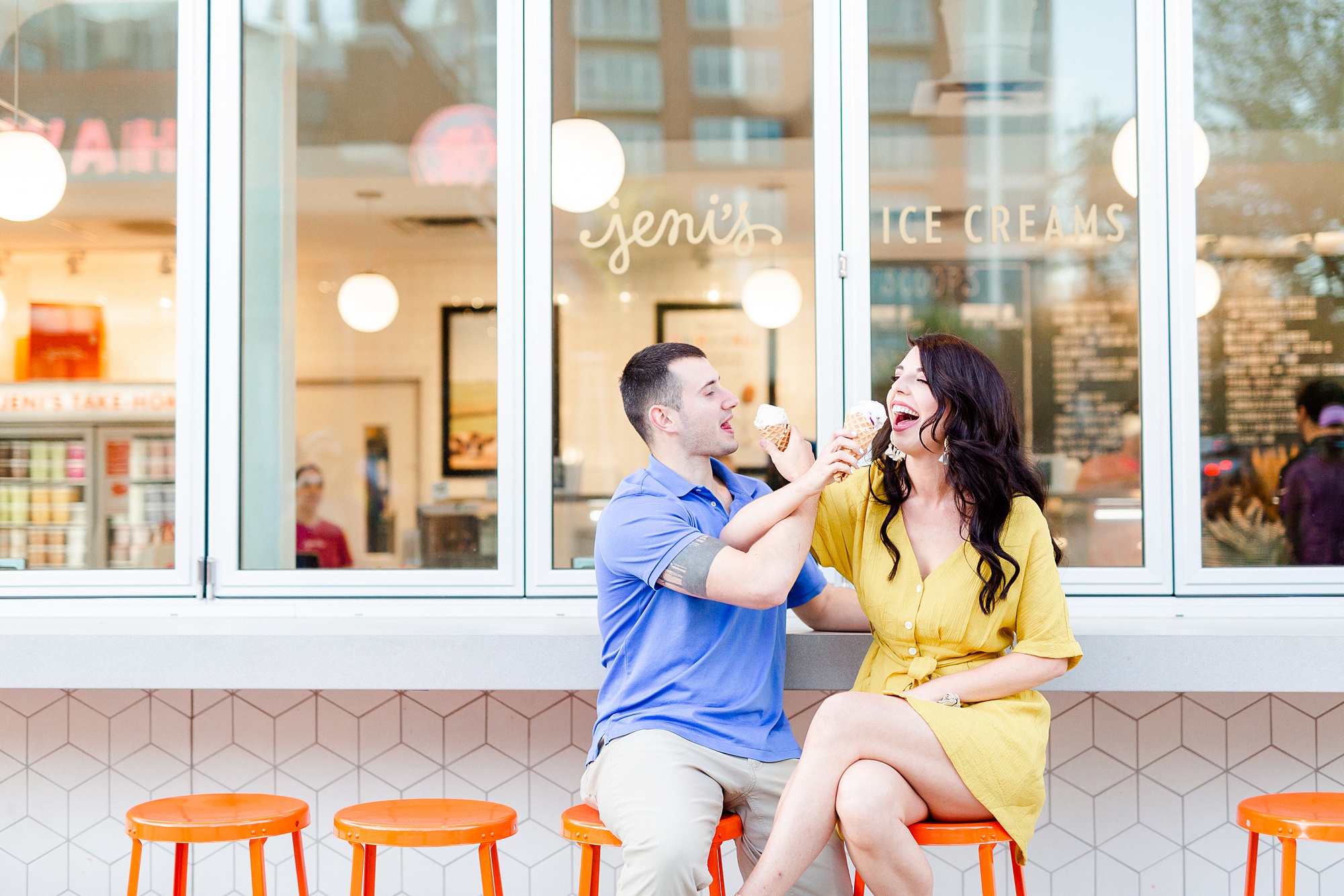 bride and groom try to feed each other ice cream at Jeni's Ice Creams