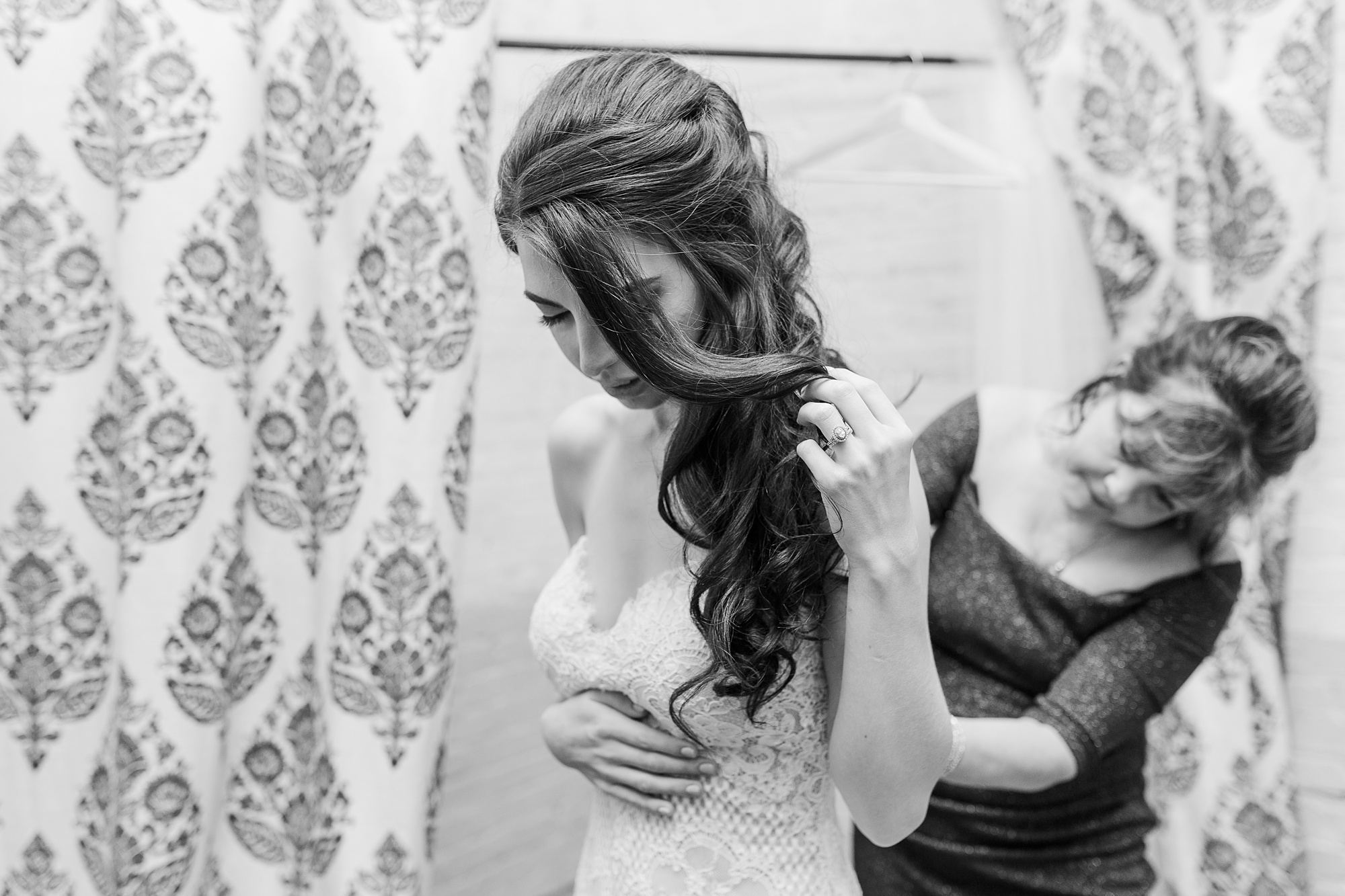 mother of bride helps bride into wedding gown
