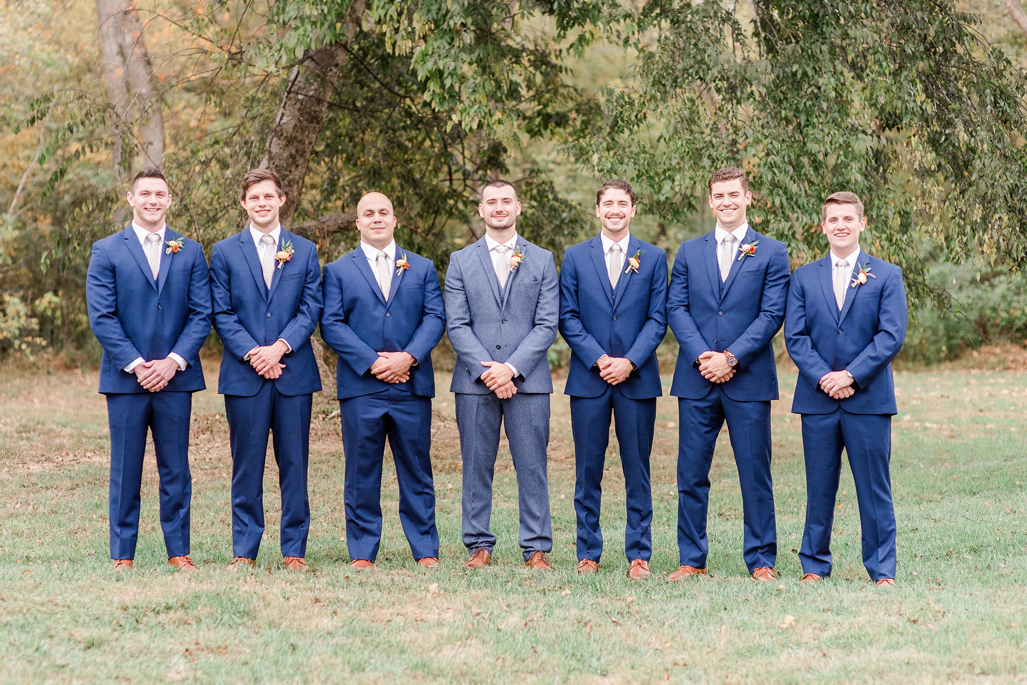 groom poses with groomsmen in navy suits