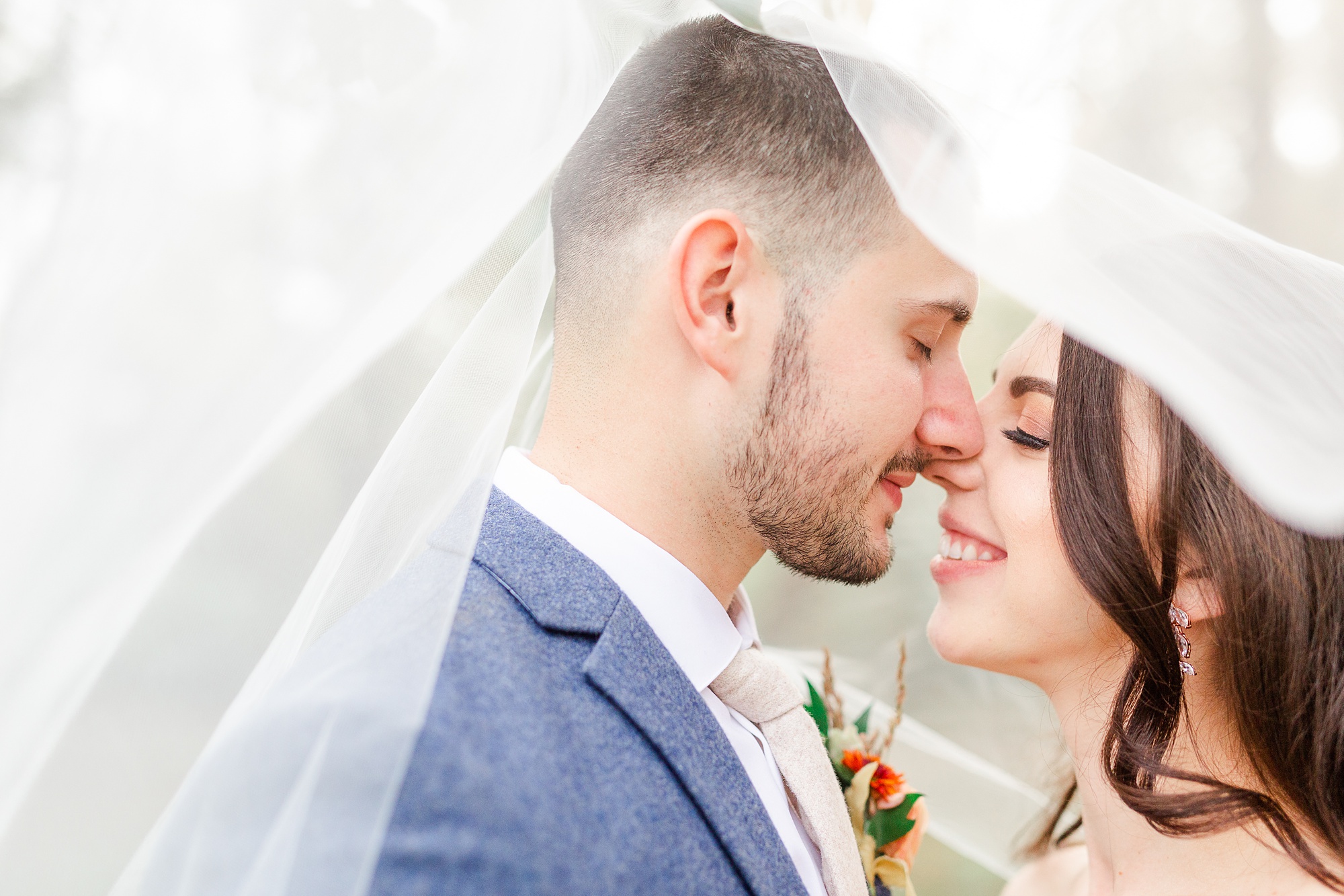 bride and groom kiss under veil