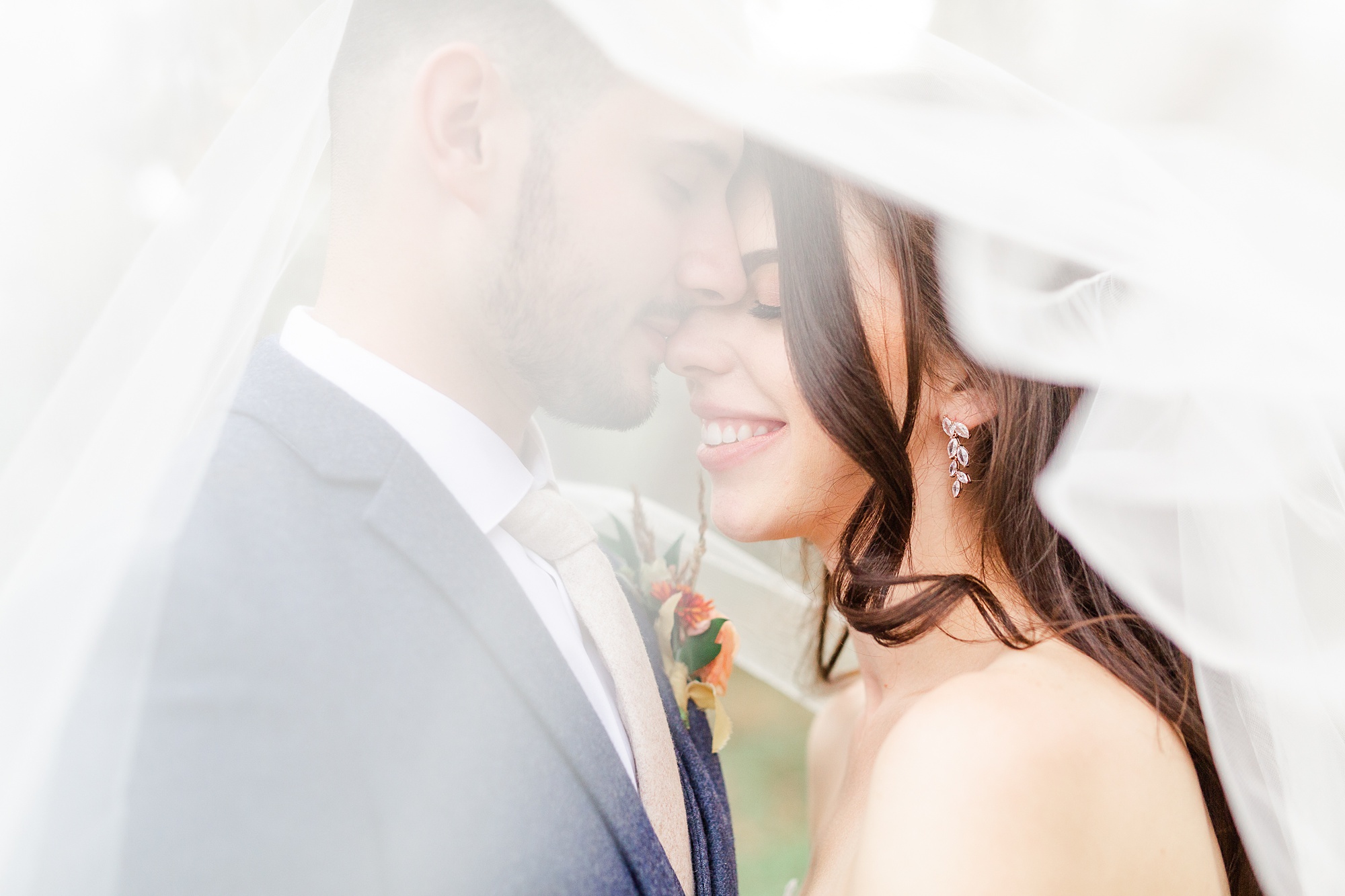 groom makes bride laugh during portraits under her veil
