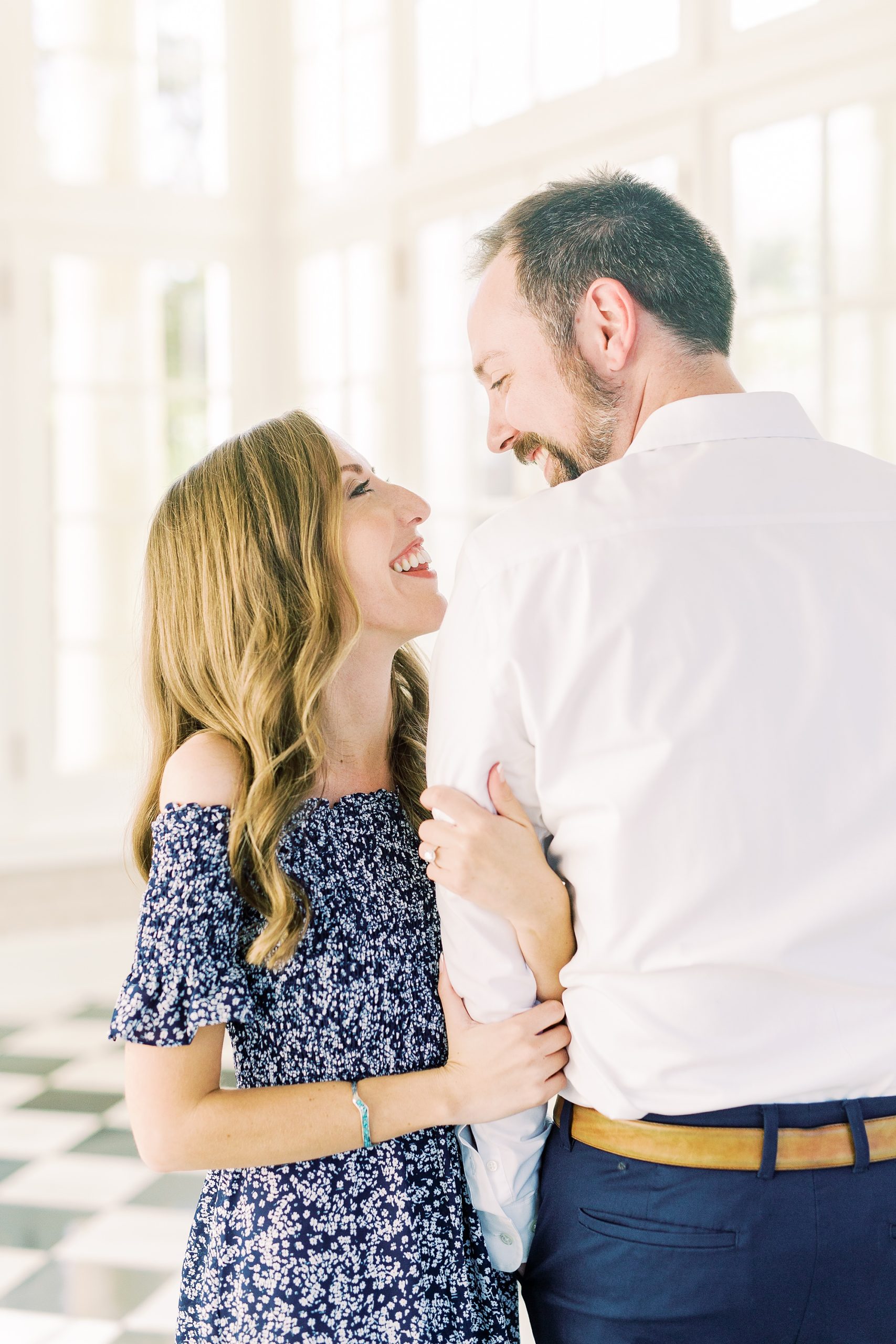bride holds groom's arm and smiles up at him