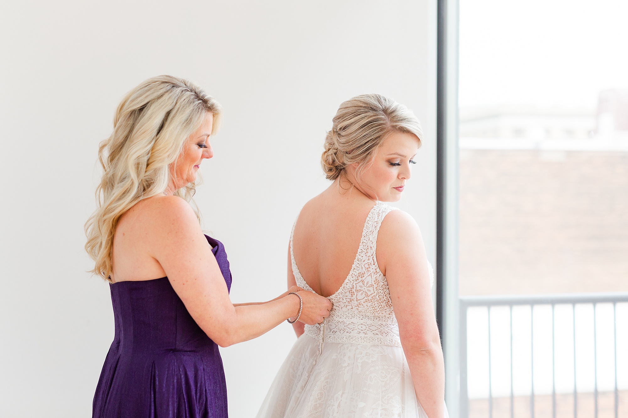 mother helps bride with wedding dress