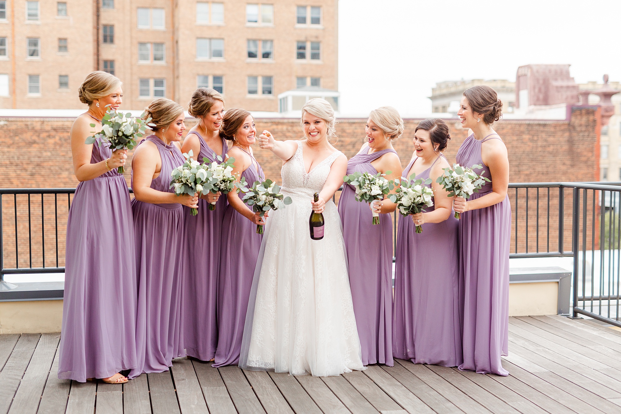 bride pops champagne during photos with bridesmaids