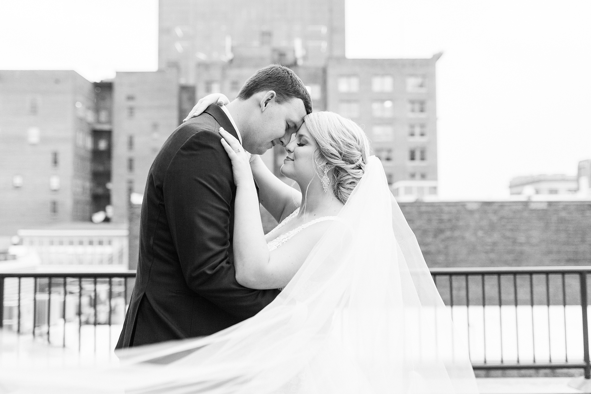 bride and groom touch noses with veil floating around them