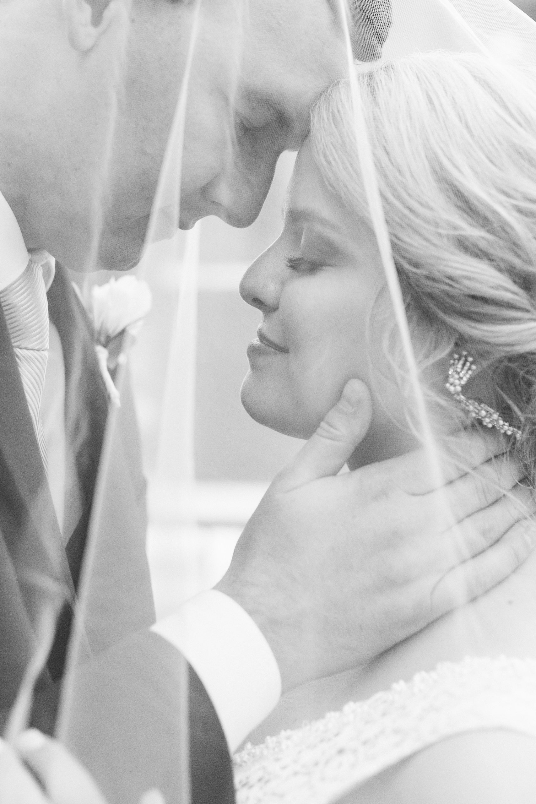 bride and groom pose under veil