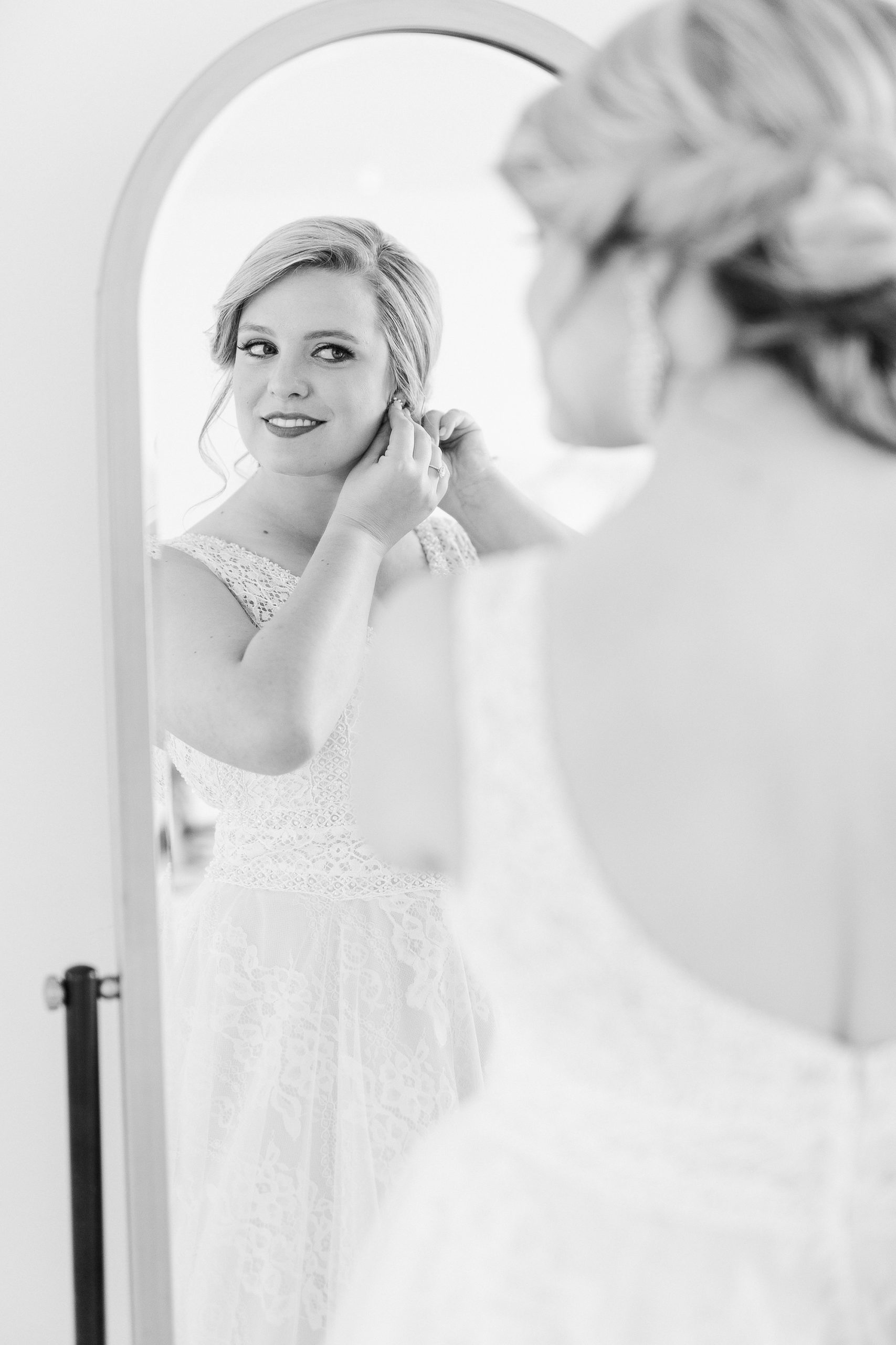bride adjusts earrings during portraits at The Glass Box