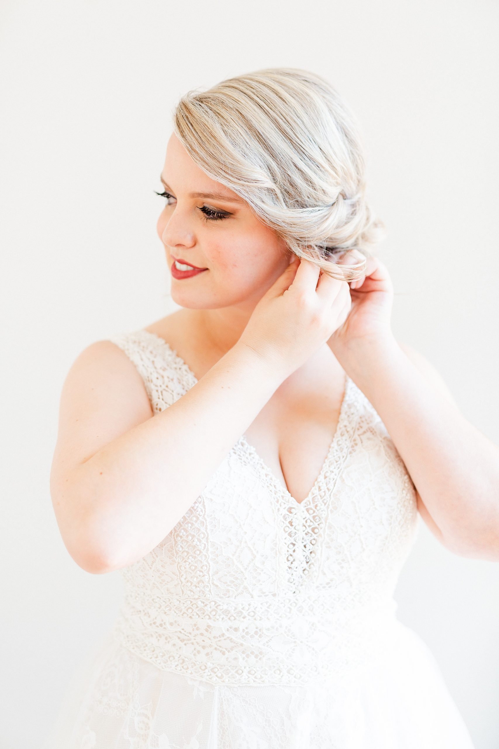 bride adjusts earrings during Raleigh NC bridal portraits