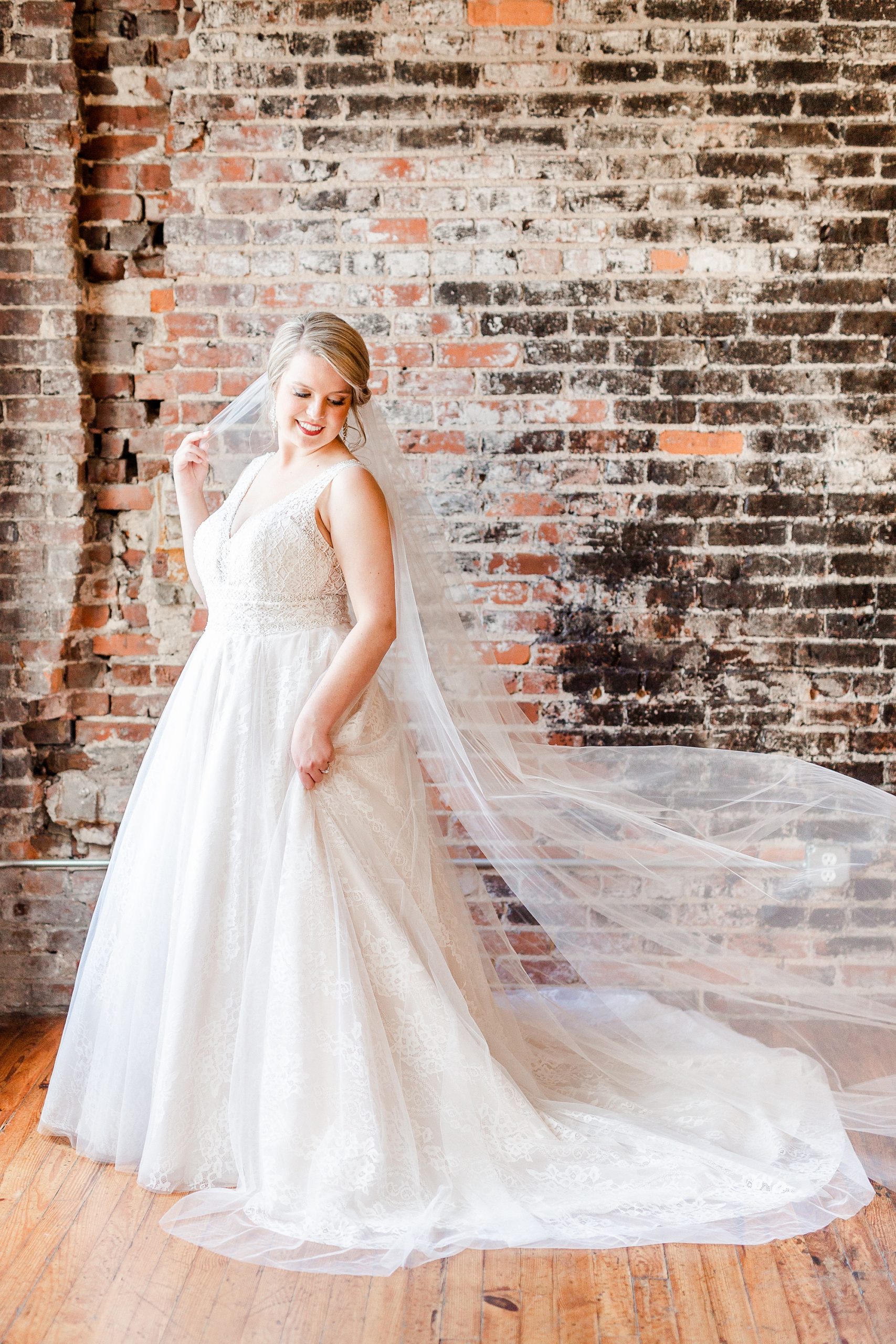 bride holds veil around shoulders during bridal portraits