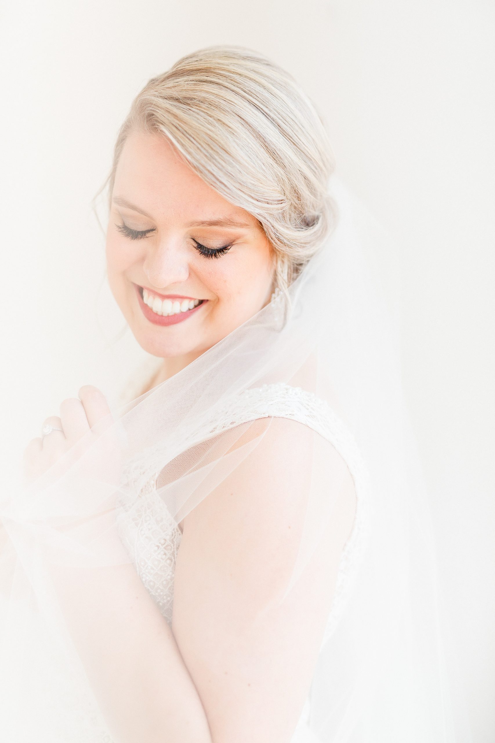 bride holds veil around shoulders