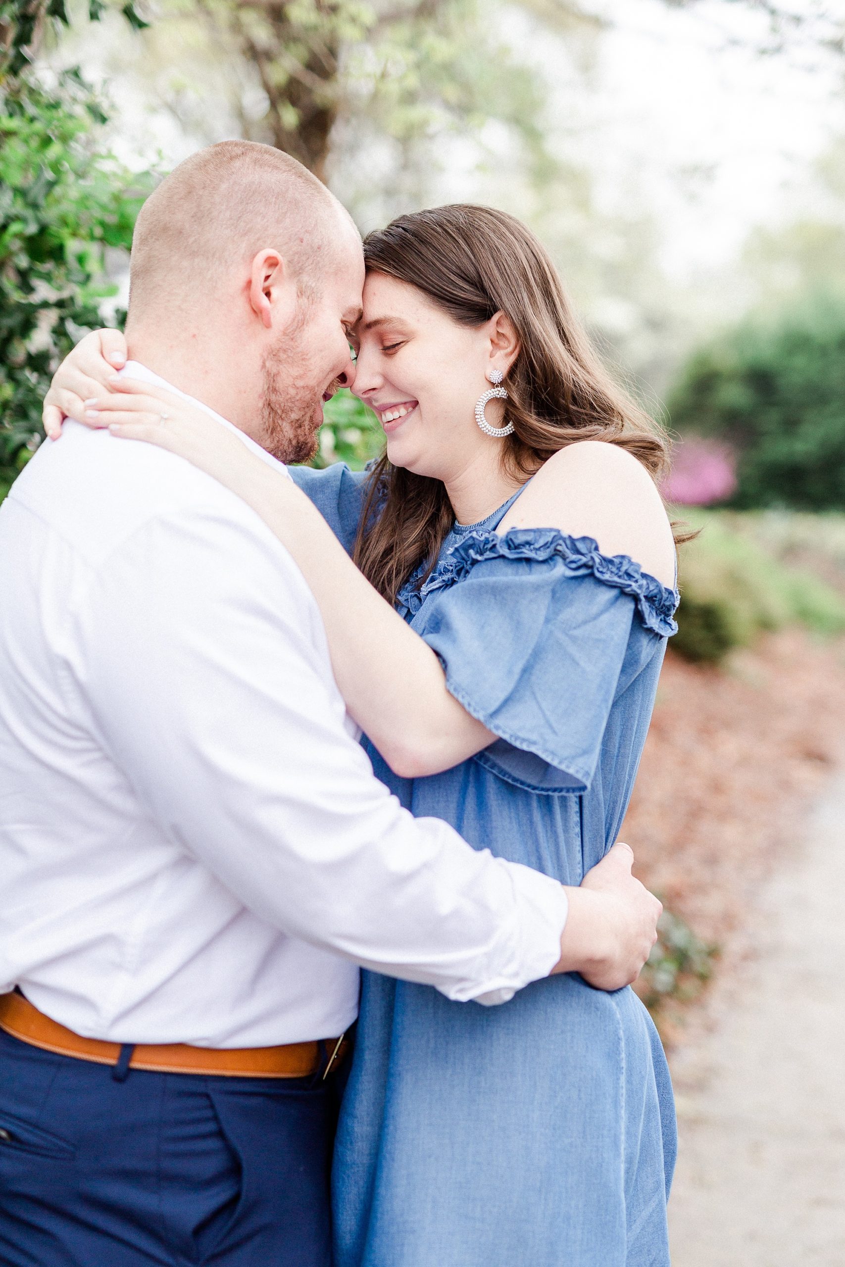 engaged couple stands nose to nose on sidewalk in Downtown Davidson