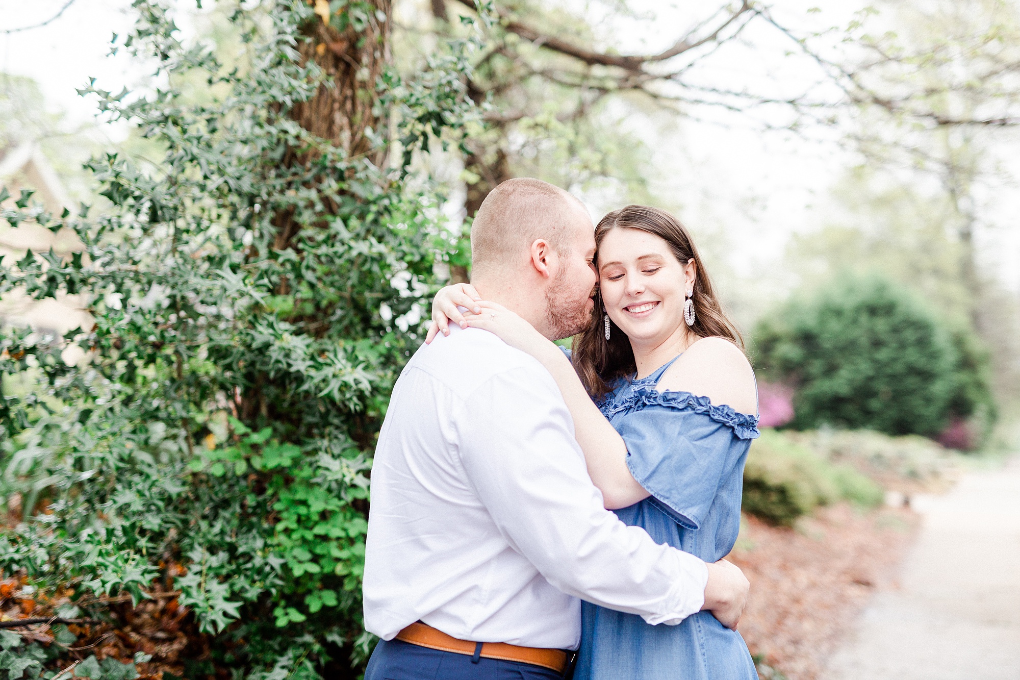 engaged couple snuggles along sidewalk in Downtown Davidson
