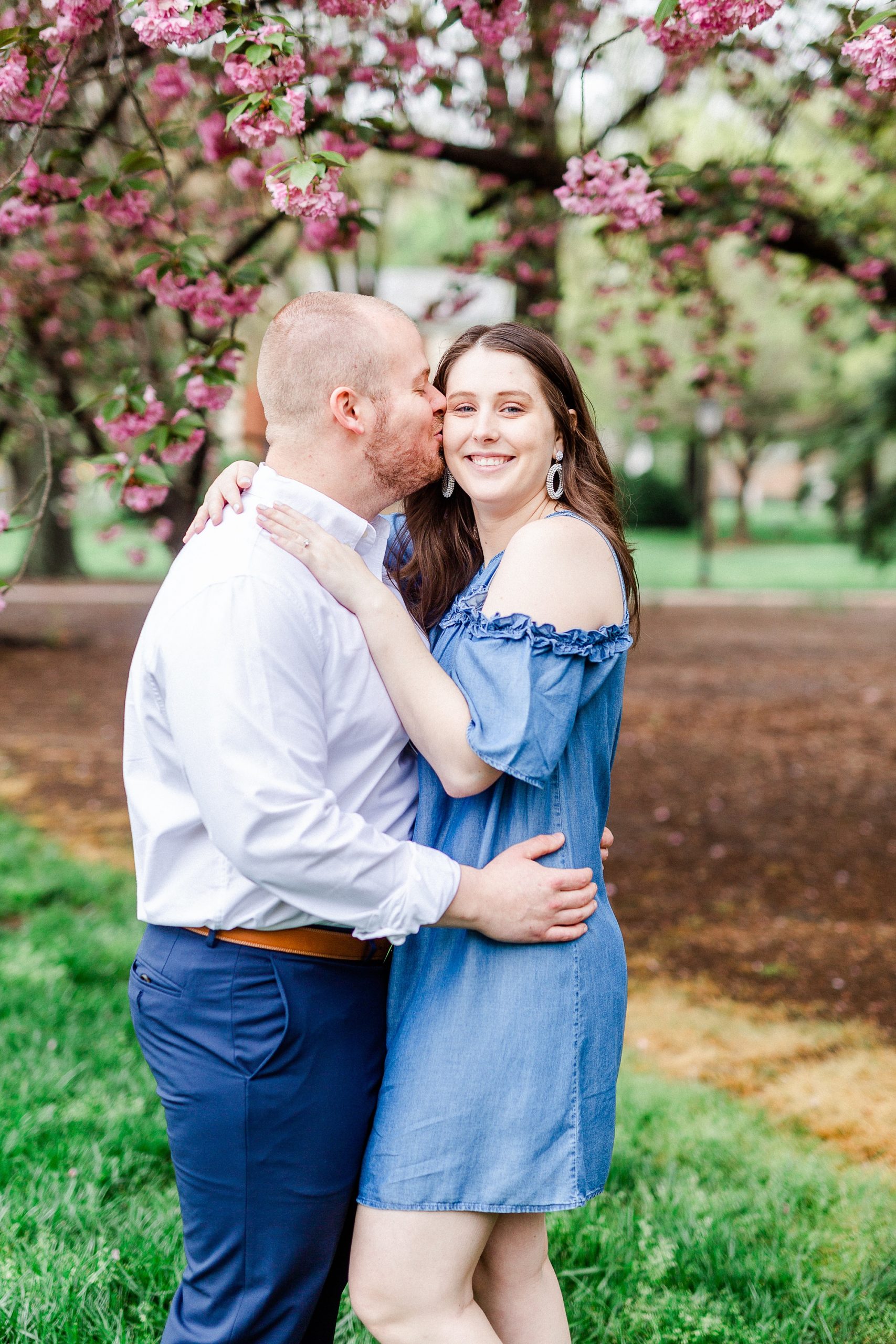 groom kisses bride under cherry blossom tree