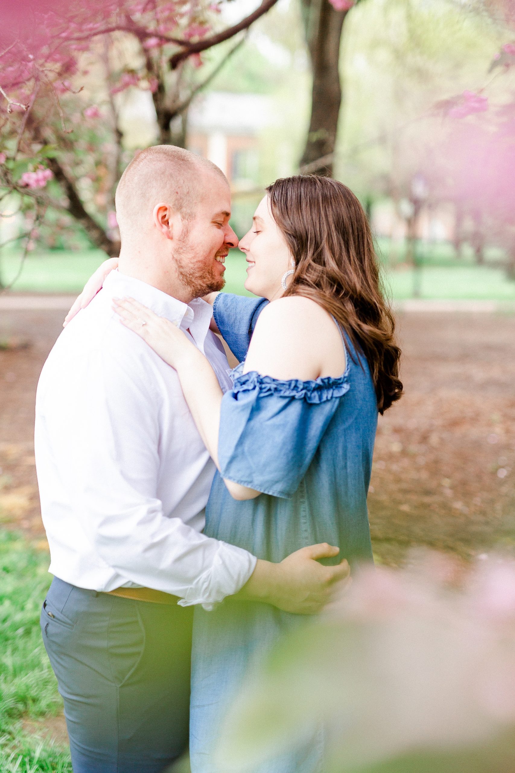 bride and groom pose nose to nose in cherry blossom tree