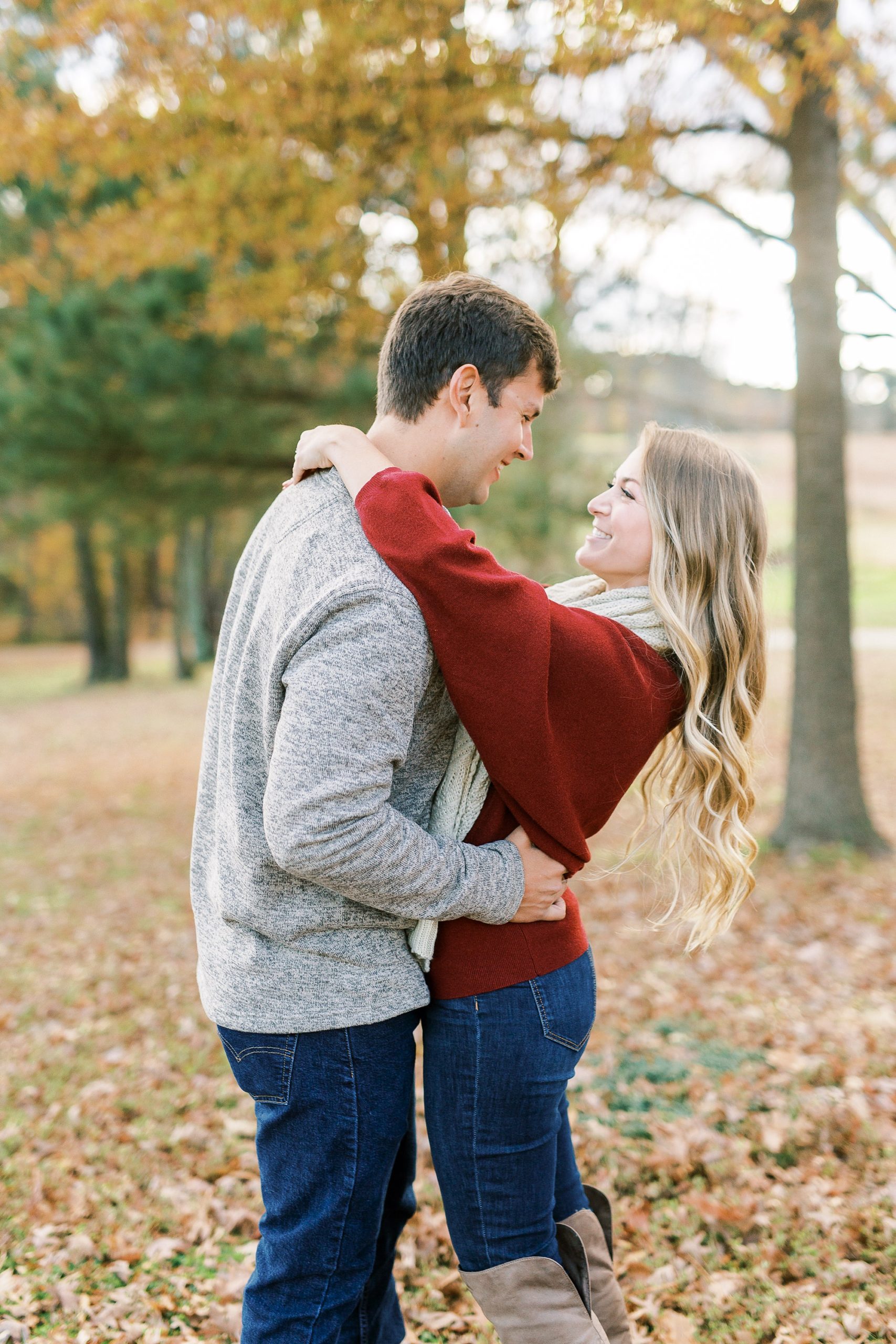 bride hugs groom around neck laughing during engagement photos