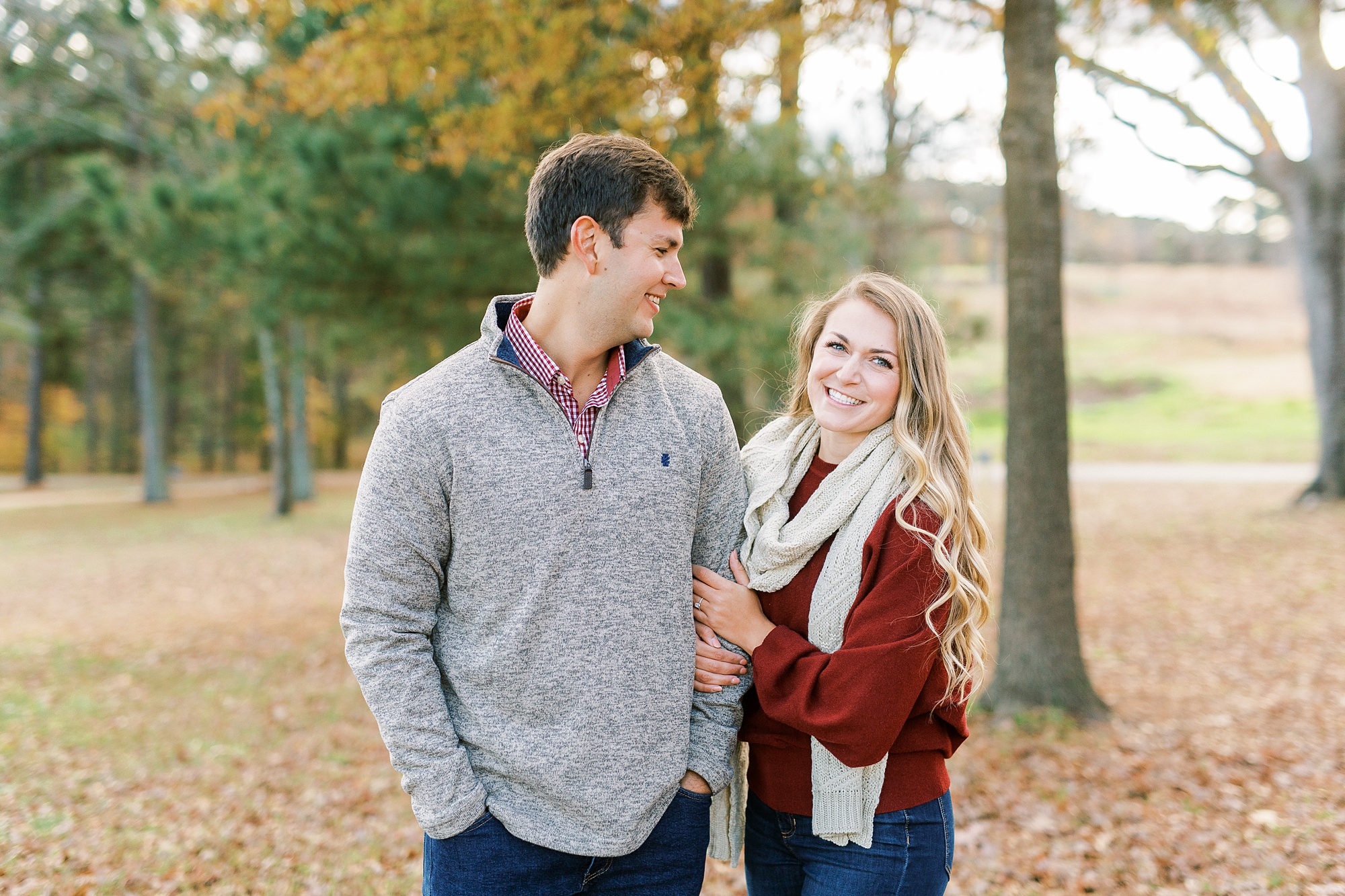 bride holds groom's arm posing during Raleigh engagement photos