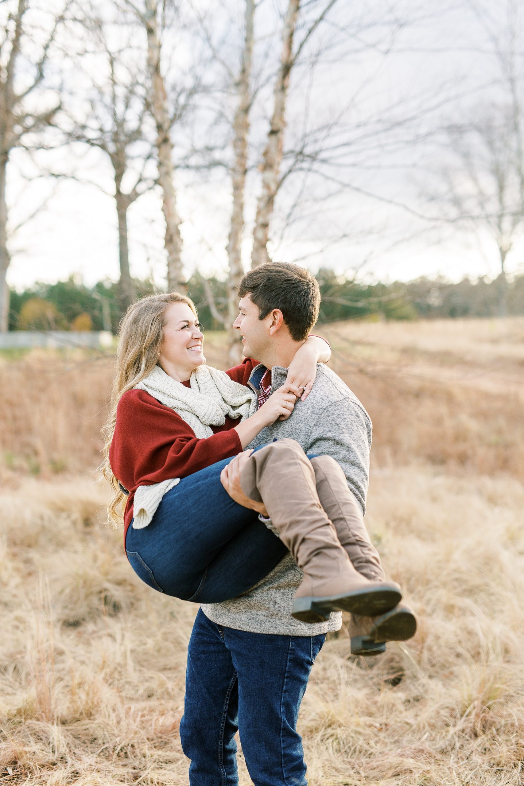 groom carries fiancee bridal style during NC Museum of Art engagement photos