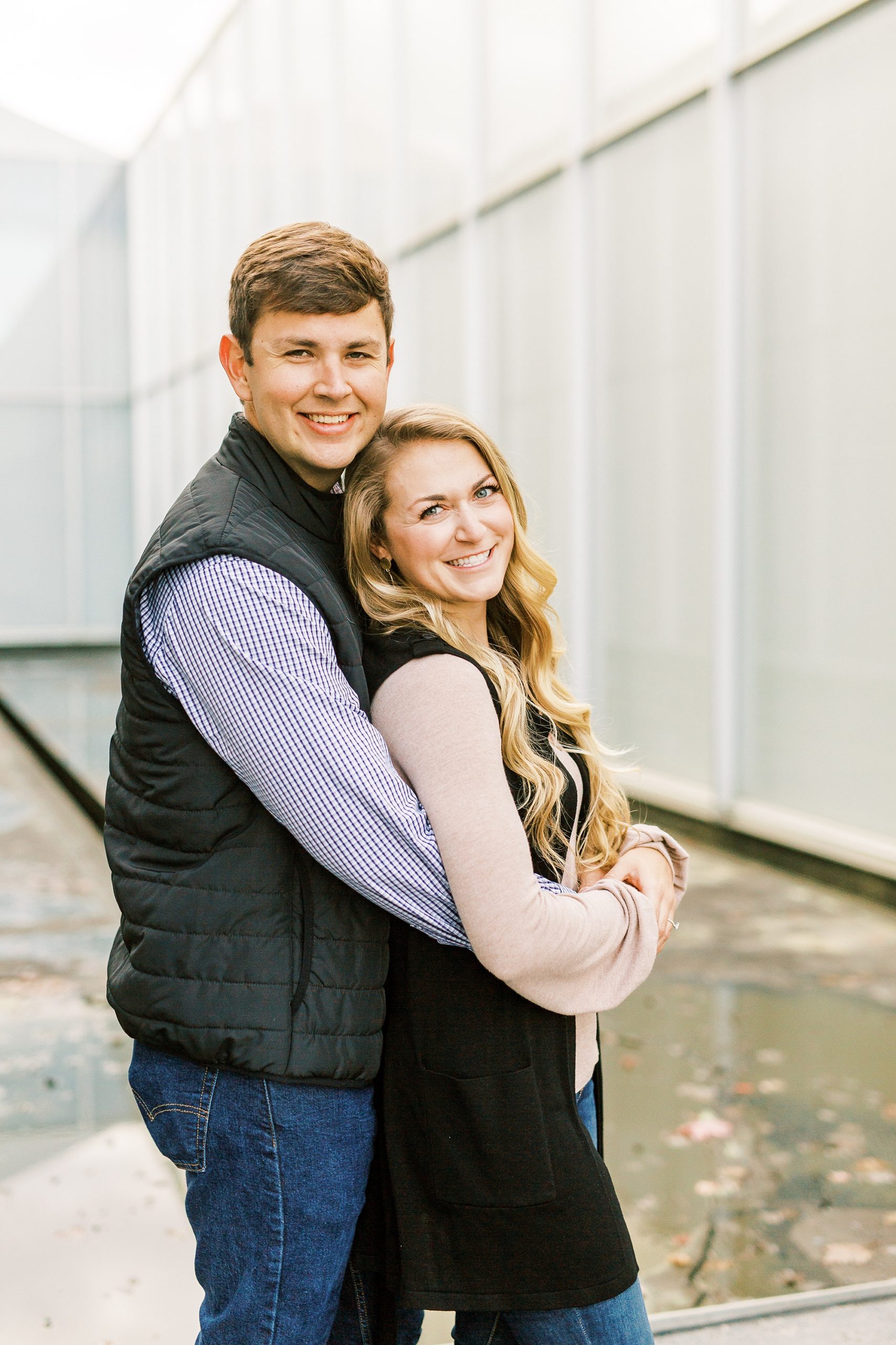 groom holds bride from behind during NC Museum of Art engagement session