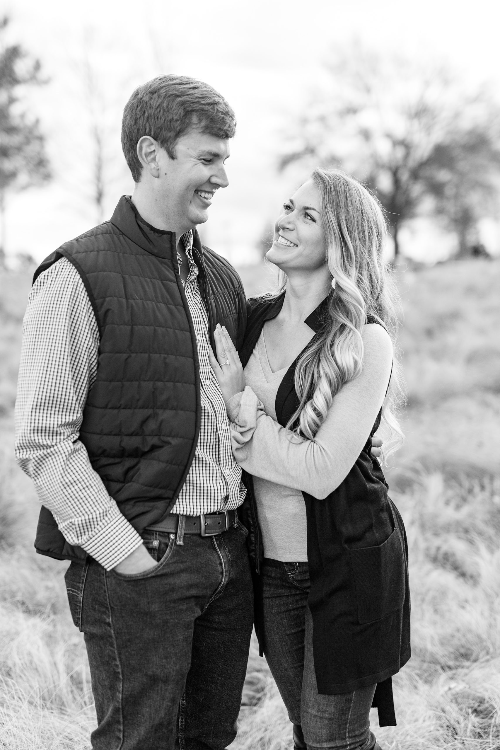 engaged couple poses in field during fall engagement photos at NC Museum of Art