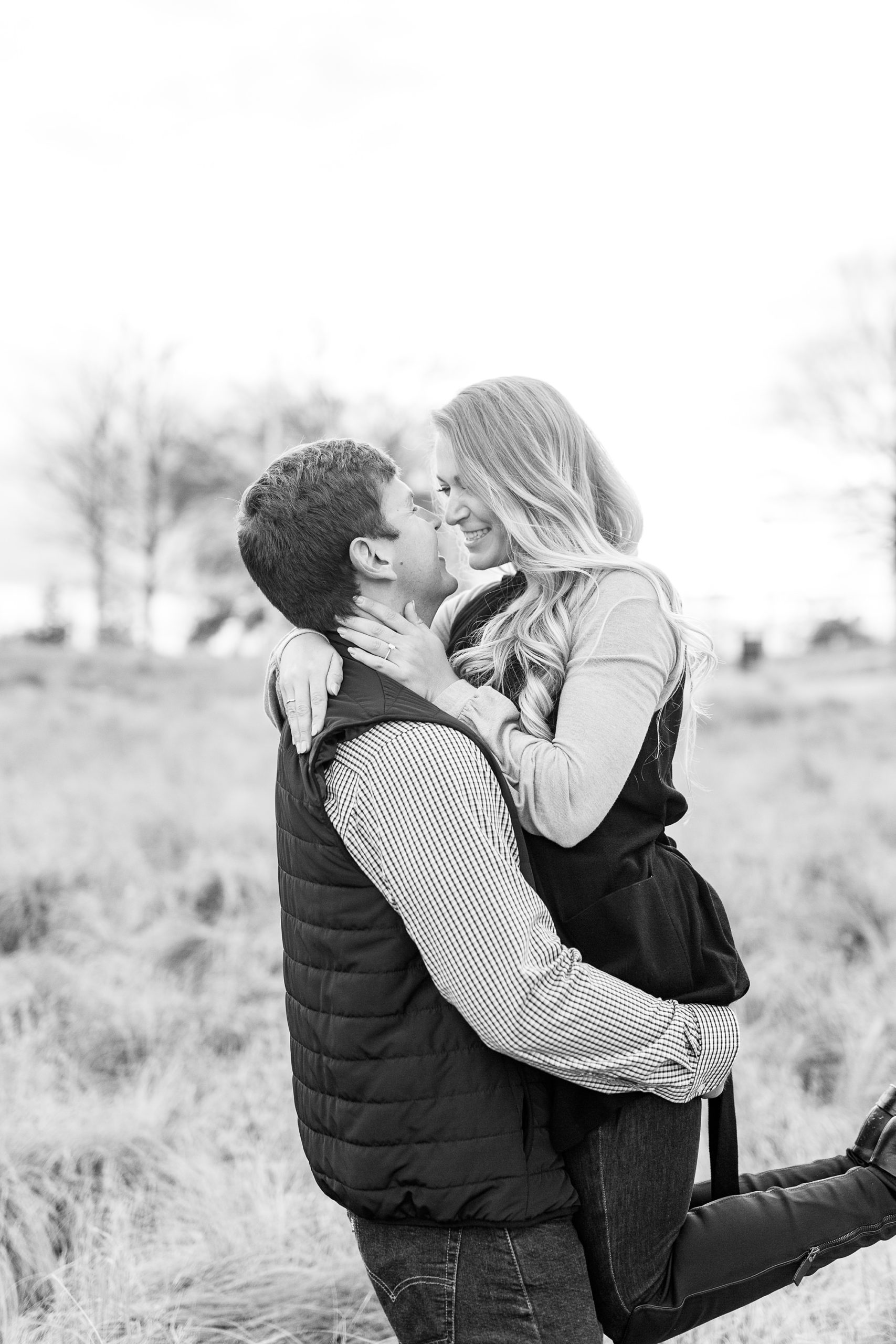groom lifts bride up during engagement photos at NC Museum of Art