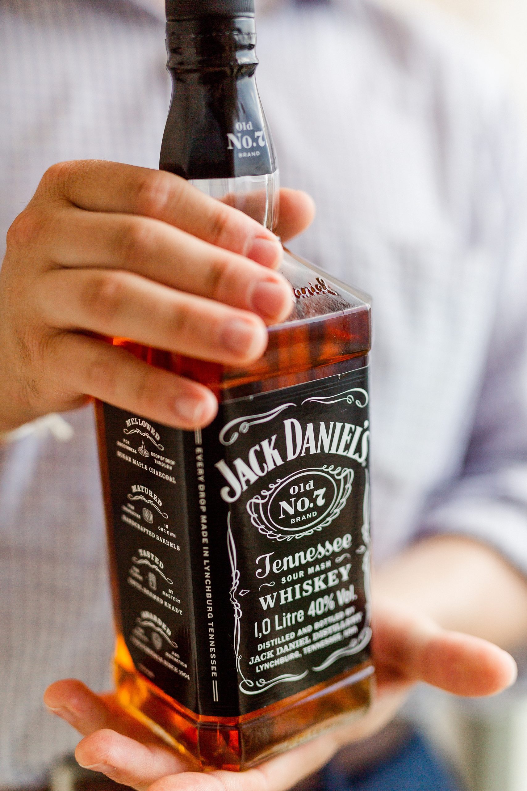 groom holds bottle of Jack Daniels before wedding ceremony