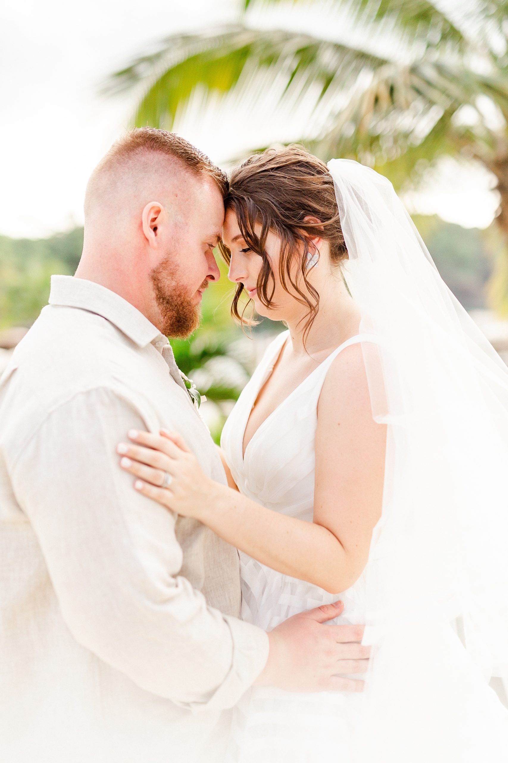 bride and groom pose together in front of palm trees before St Lucia resort wedding