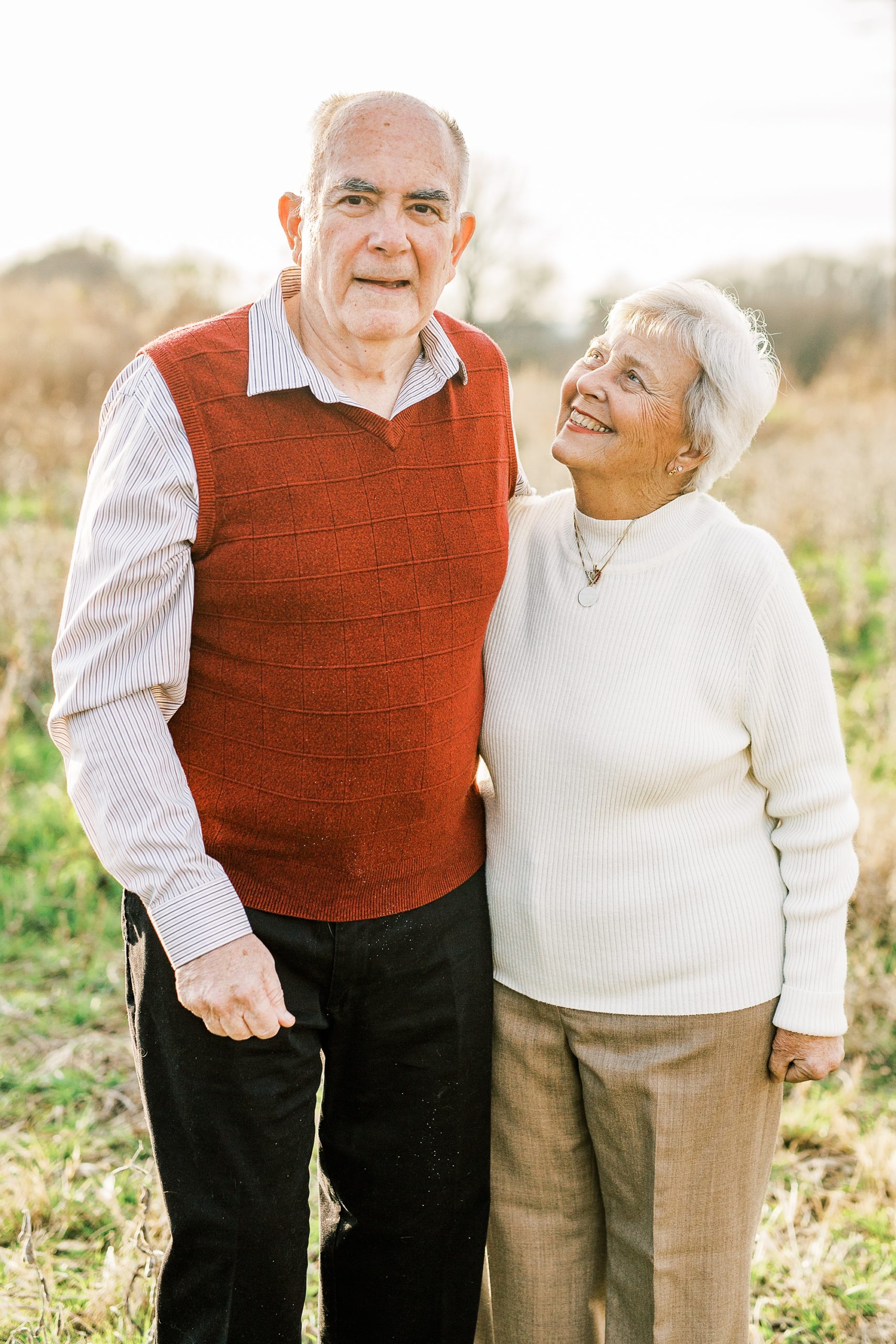husband and wife pose together in field during 50th anniversary photos