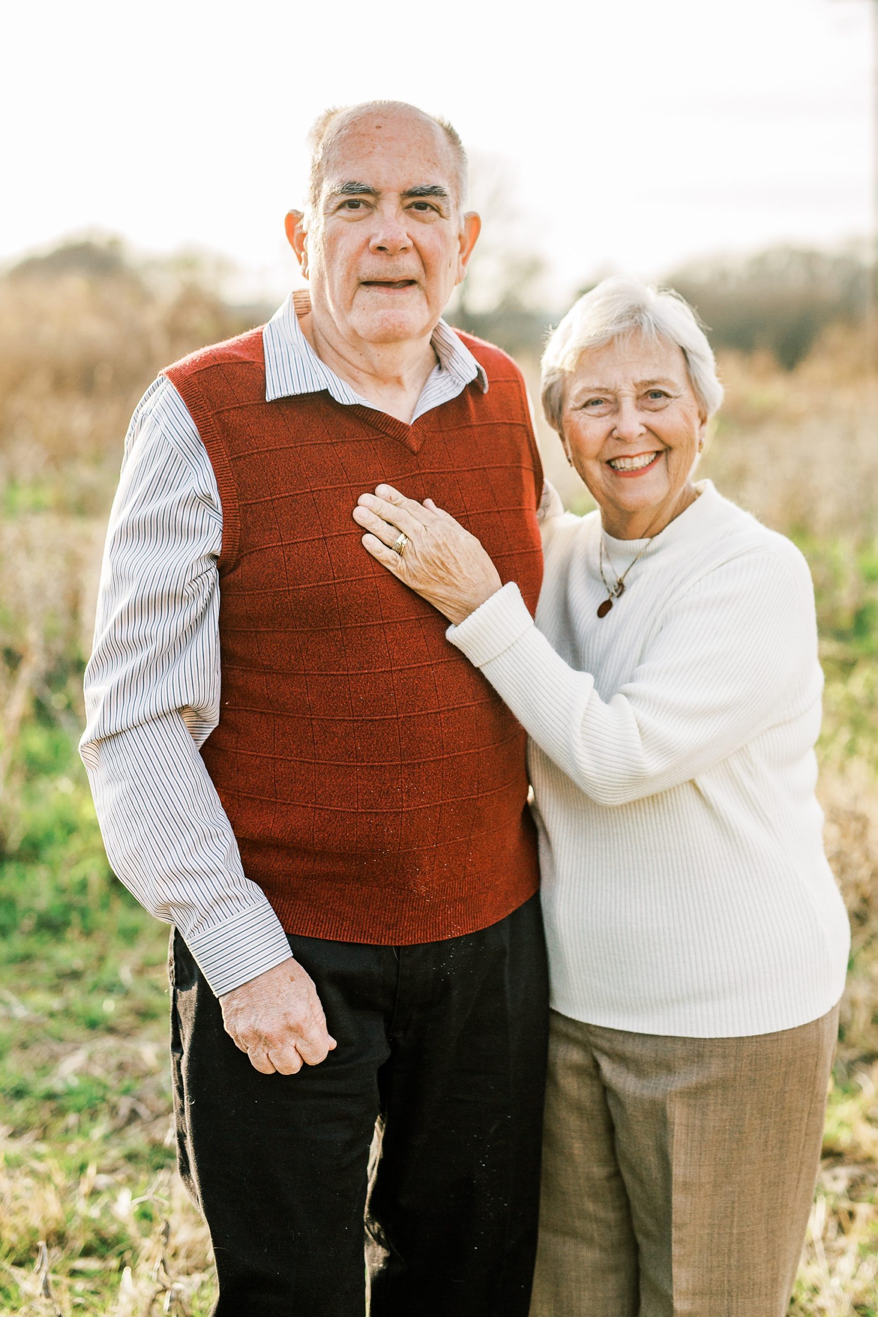 husband and wife pose in field during 50th anniversary photos