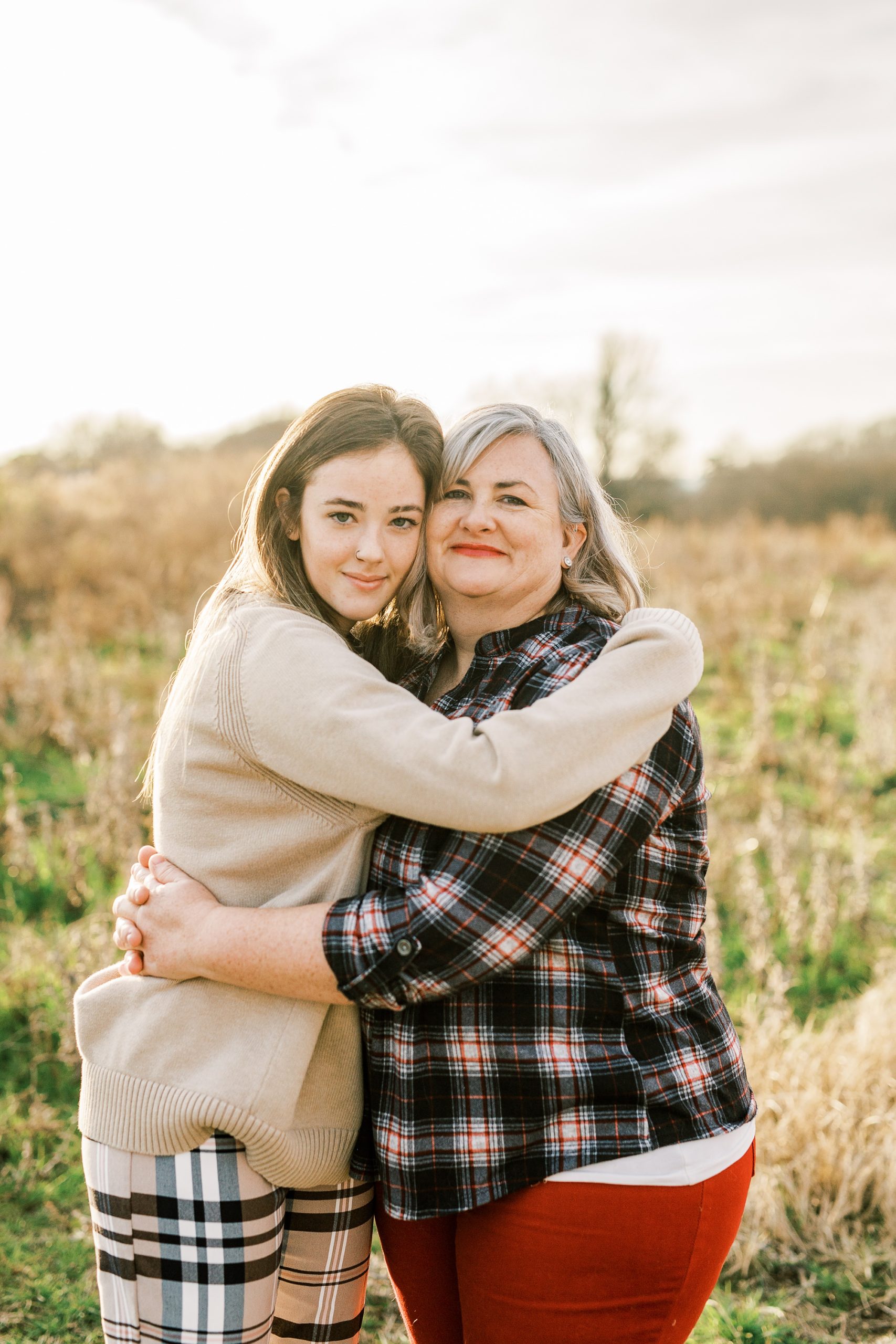 mom and daughter hug on edge of field in Charlotte NC