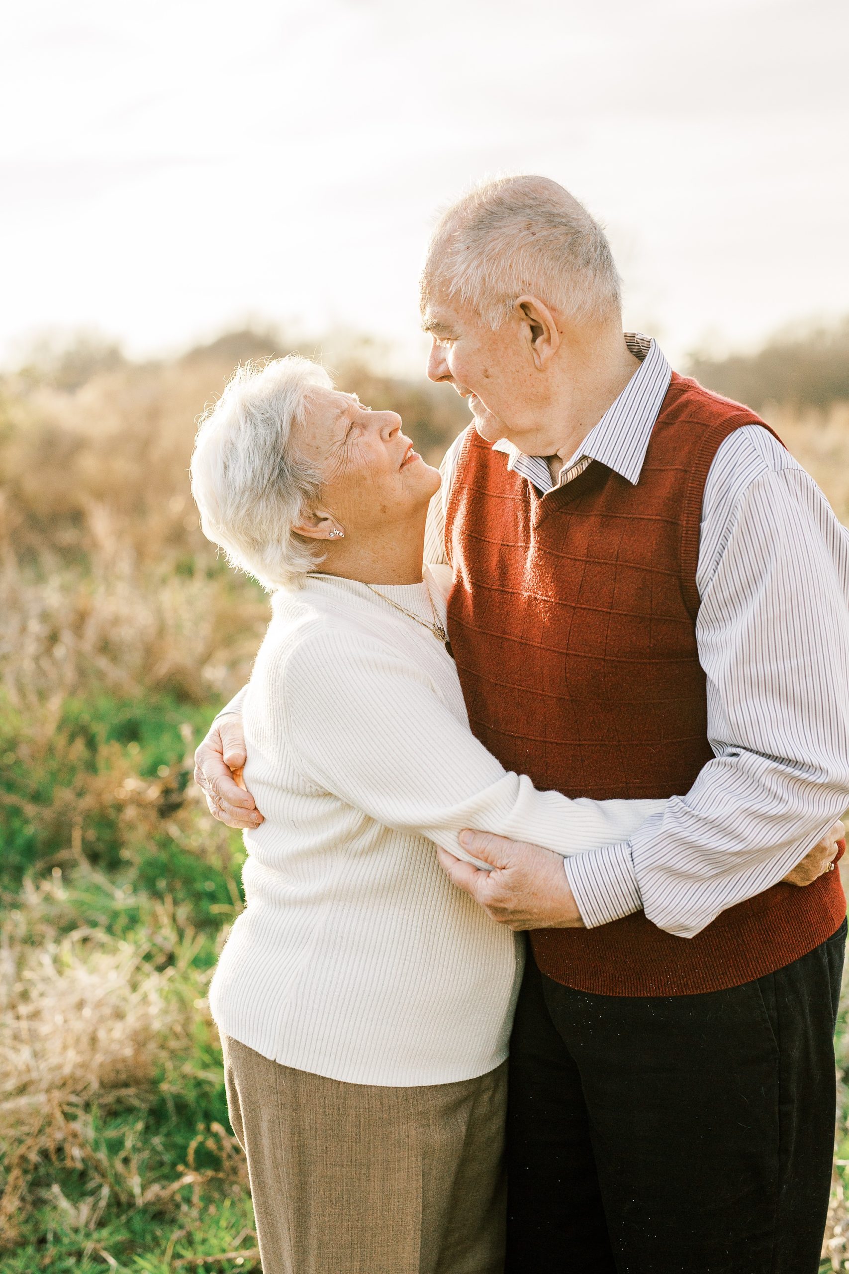 husband and wife pose together in field during winter 50th anniversary photos