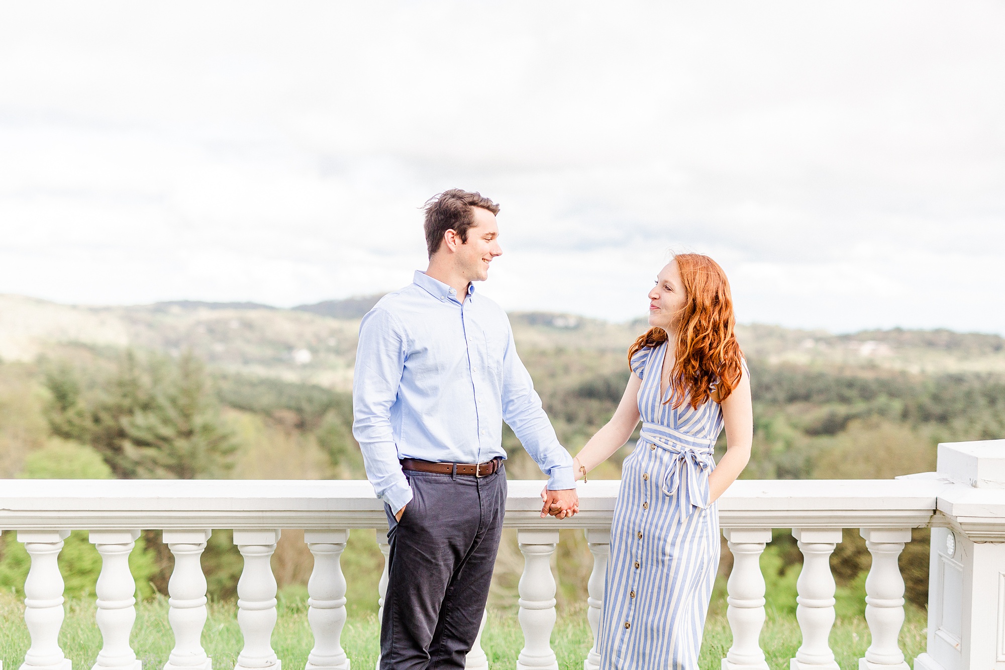 engaged couple holds hands walking along balcony