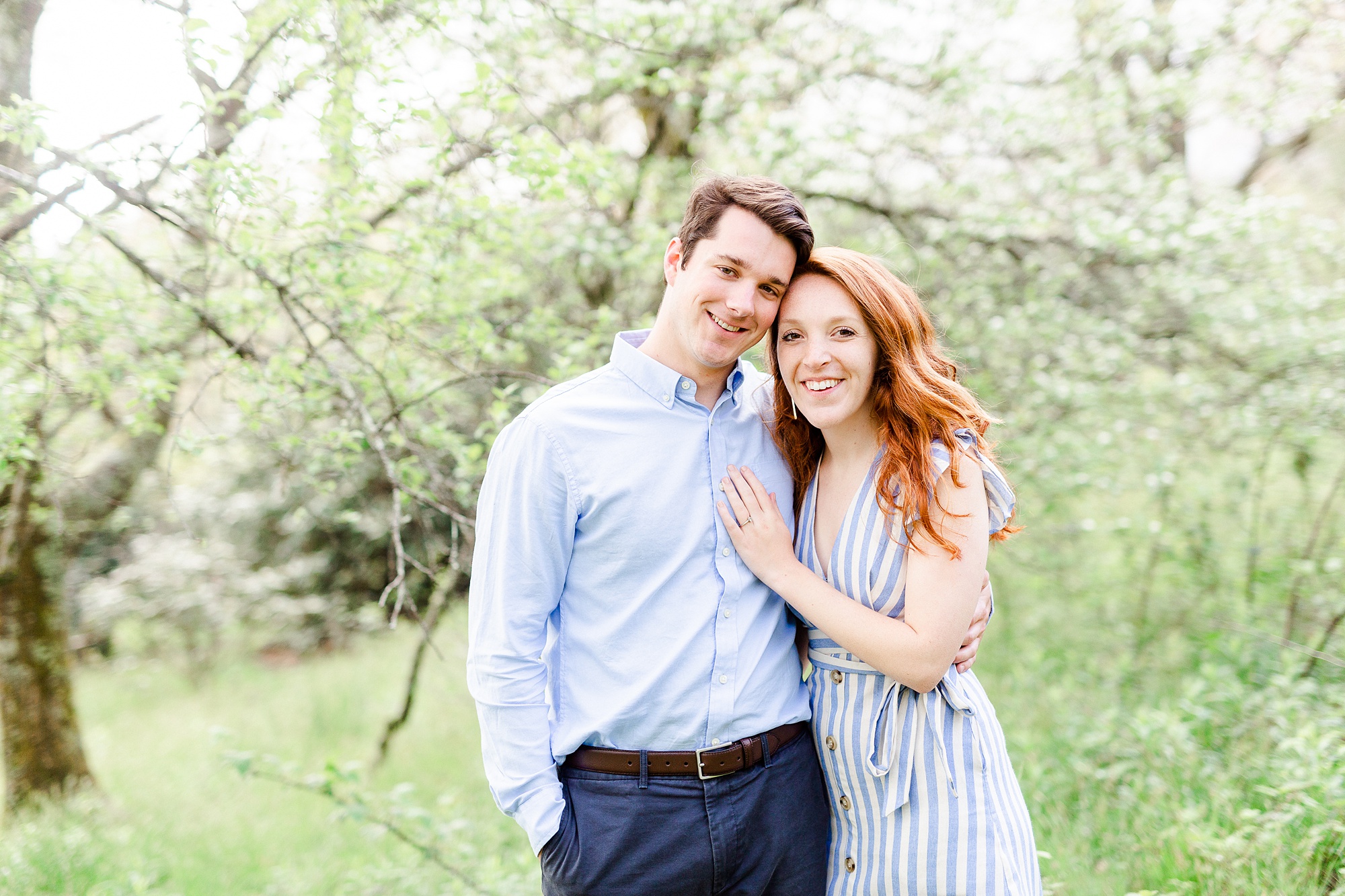 bride and groom pose in front of spring tree