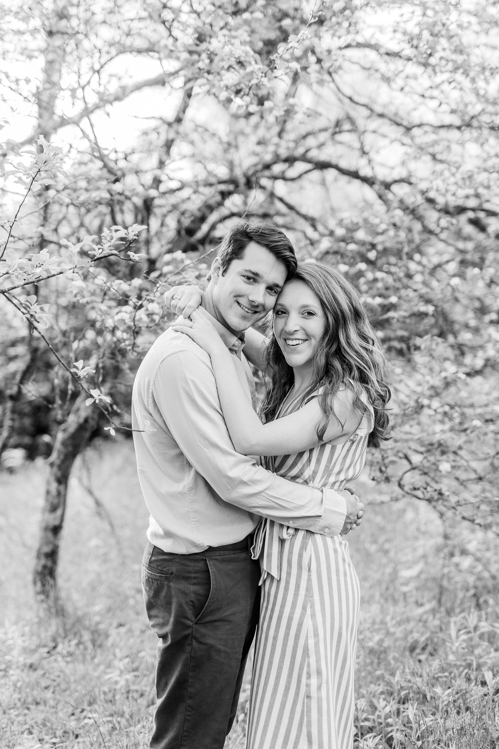 bride and groom hug in front of tree during spring engagement session